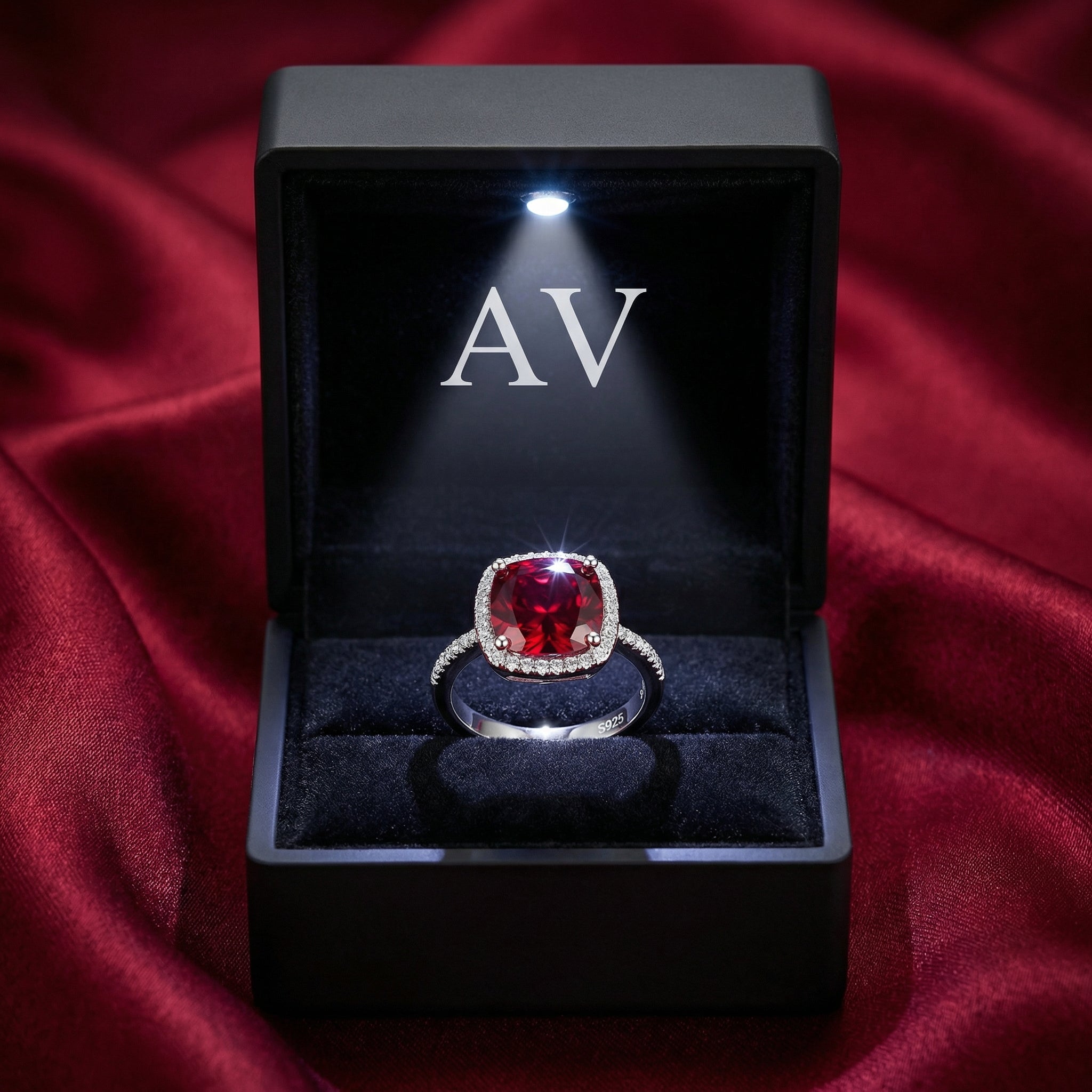 Cushion-cut simulated ruby sterling silver ring presented in a black LED-lit jewelry gift box.