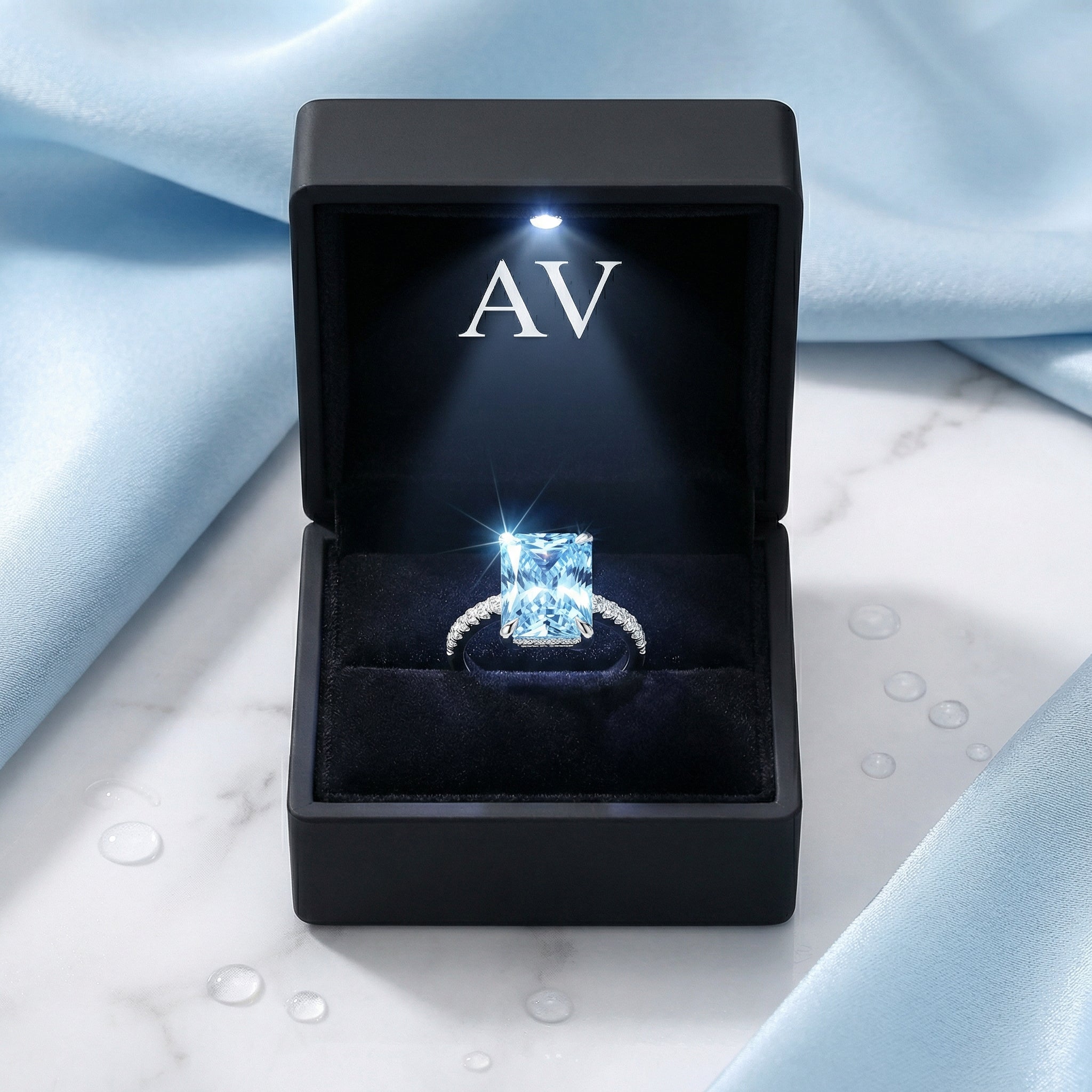 Radiant-cut simulated aquamarine sterling silver ring in a black LED-lit presentation box.