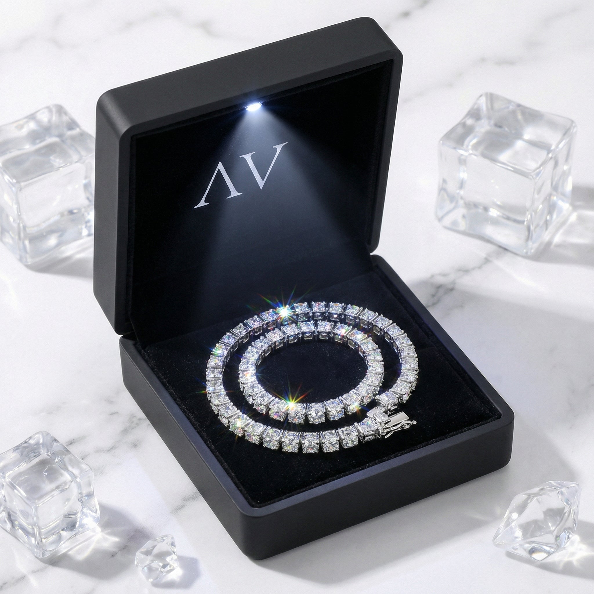 Aris round zirconia tennis bracelet in a black LED-lit gift box on a marble surface with ice cubes.