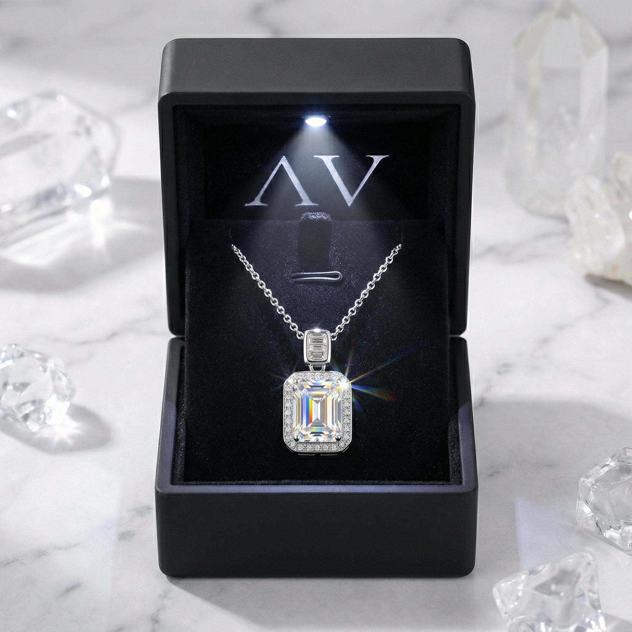 Silver emerald cut zirconia necklace displayed in a black LED-lit gift box on a marble surface.
