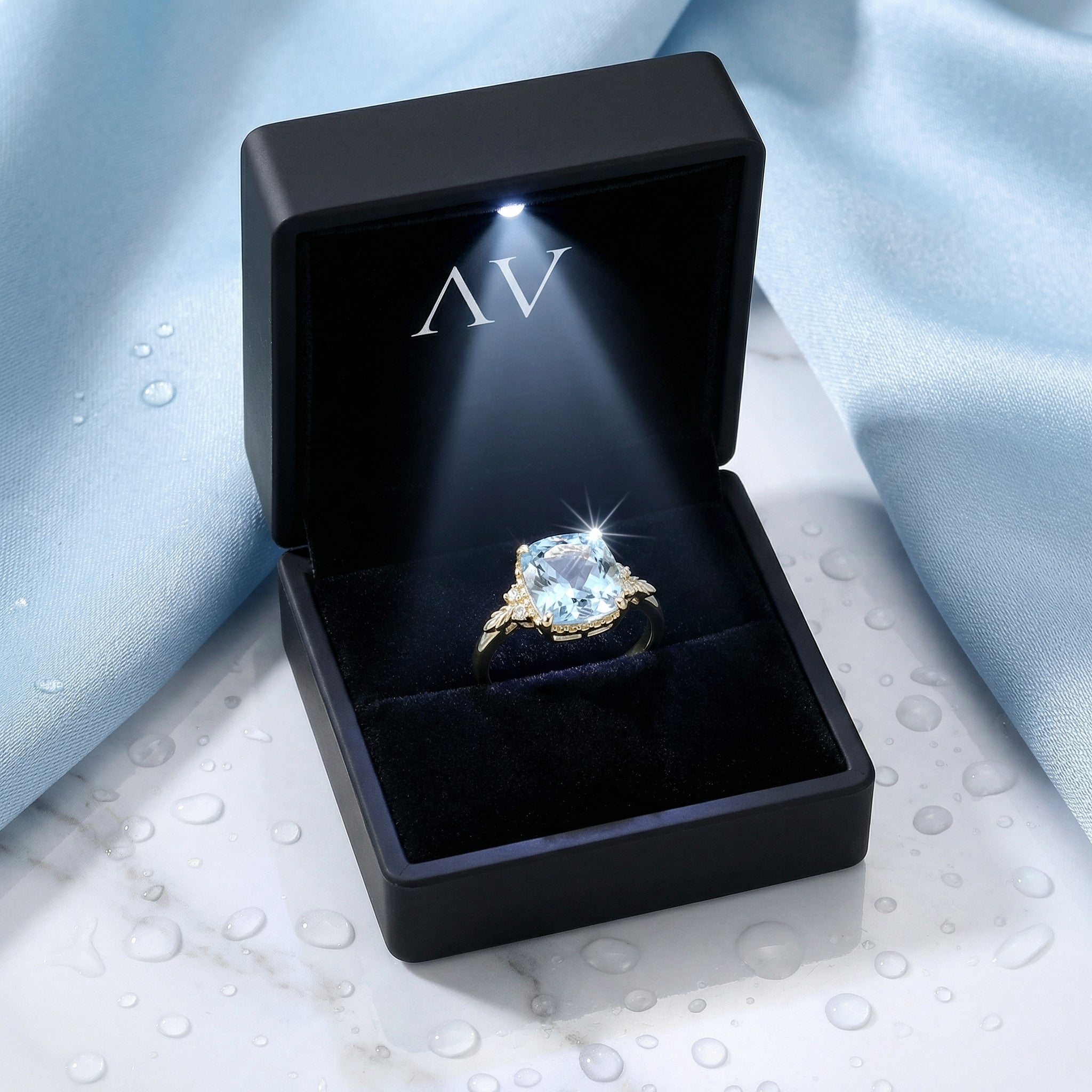 Cushion cut simulated aquamarine ring in 18K gold vermeil inside a black LED-lit jewelry box.