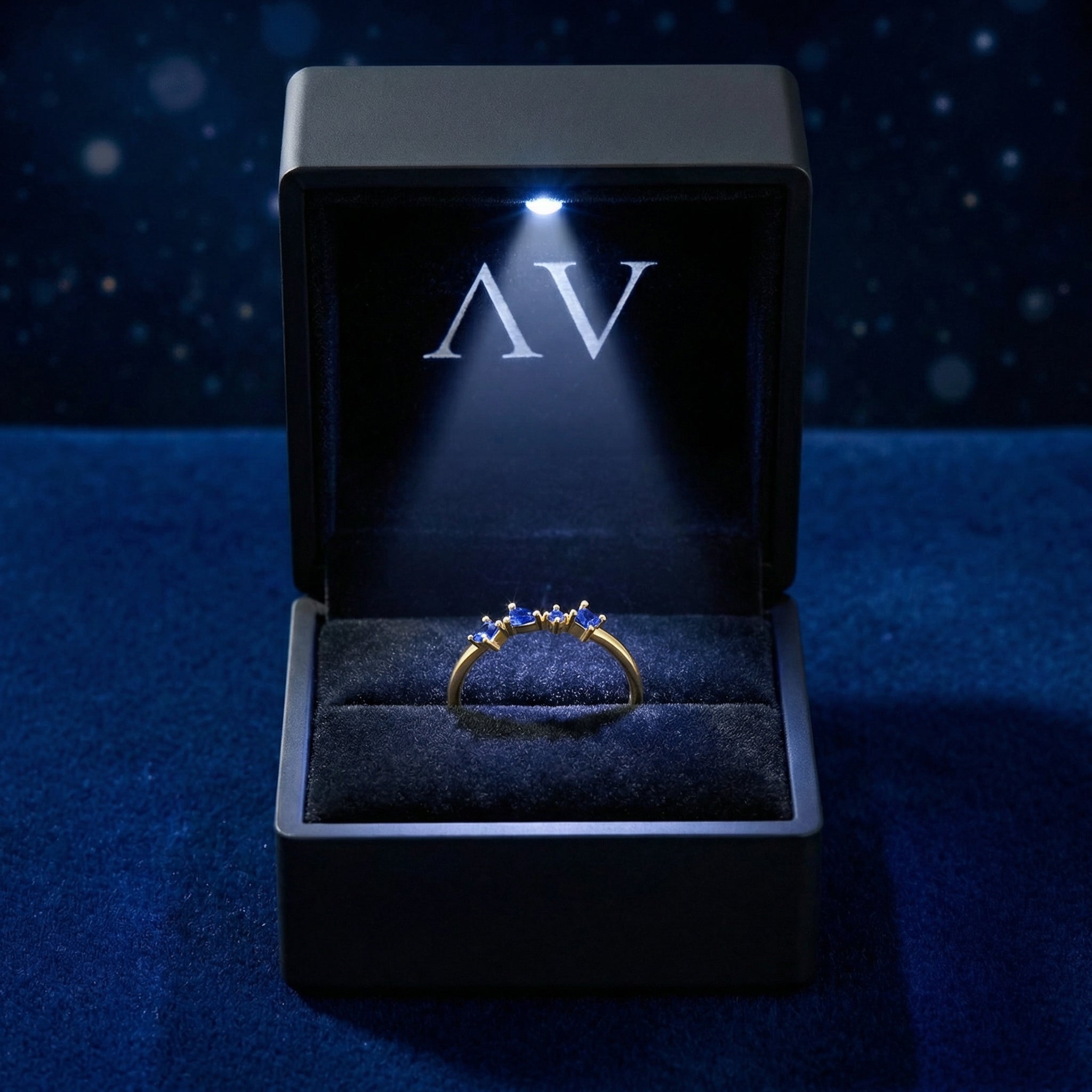Nyara V-ring with simulated blue sapphires inside a black LED-lighted jewelry box with AV branding.