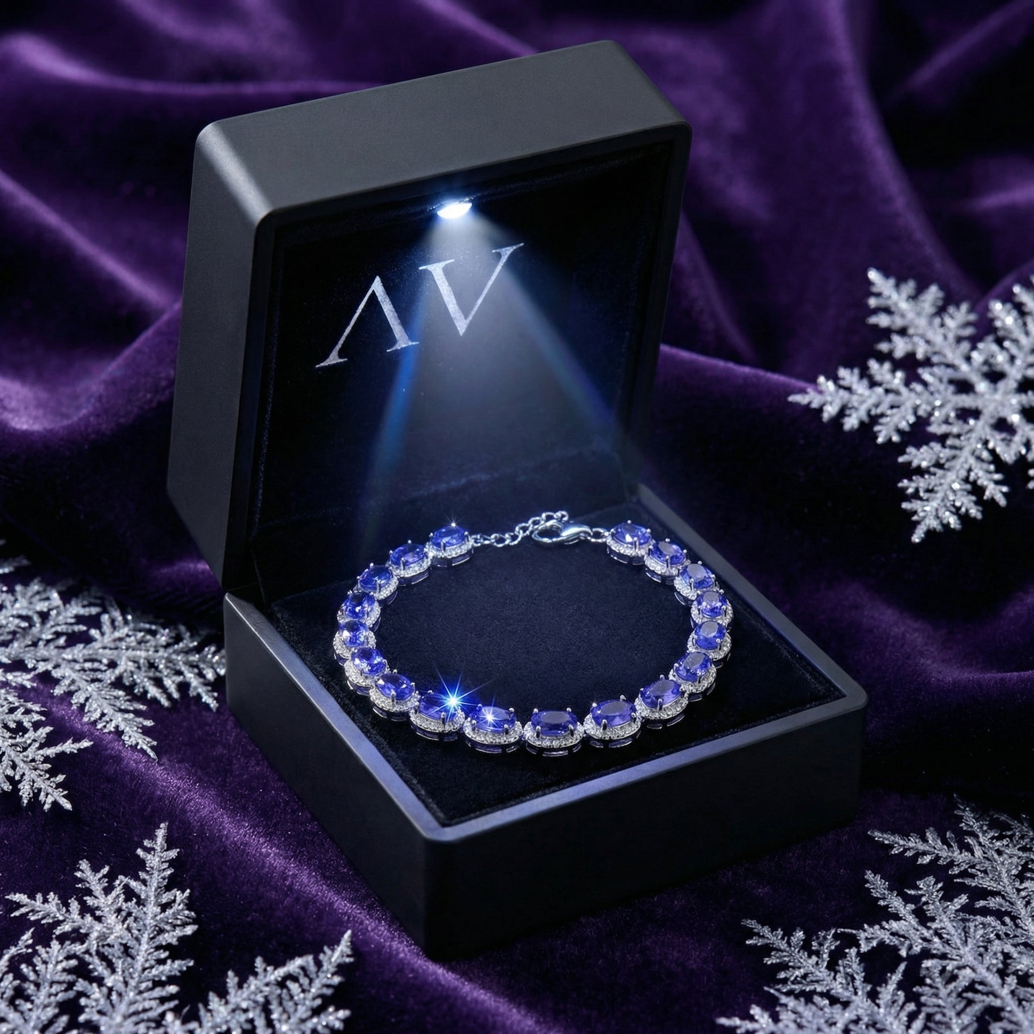 Sterling silver simulated tanzanite tennis bracelet in a lighted black gift box on purple velvet.