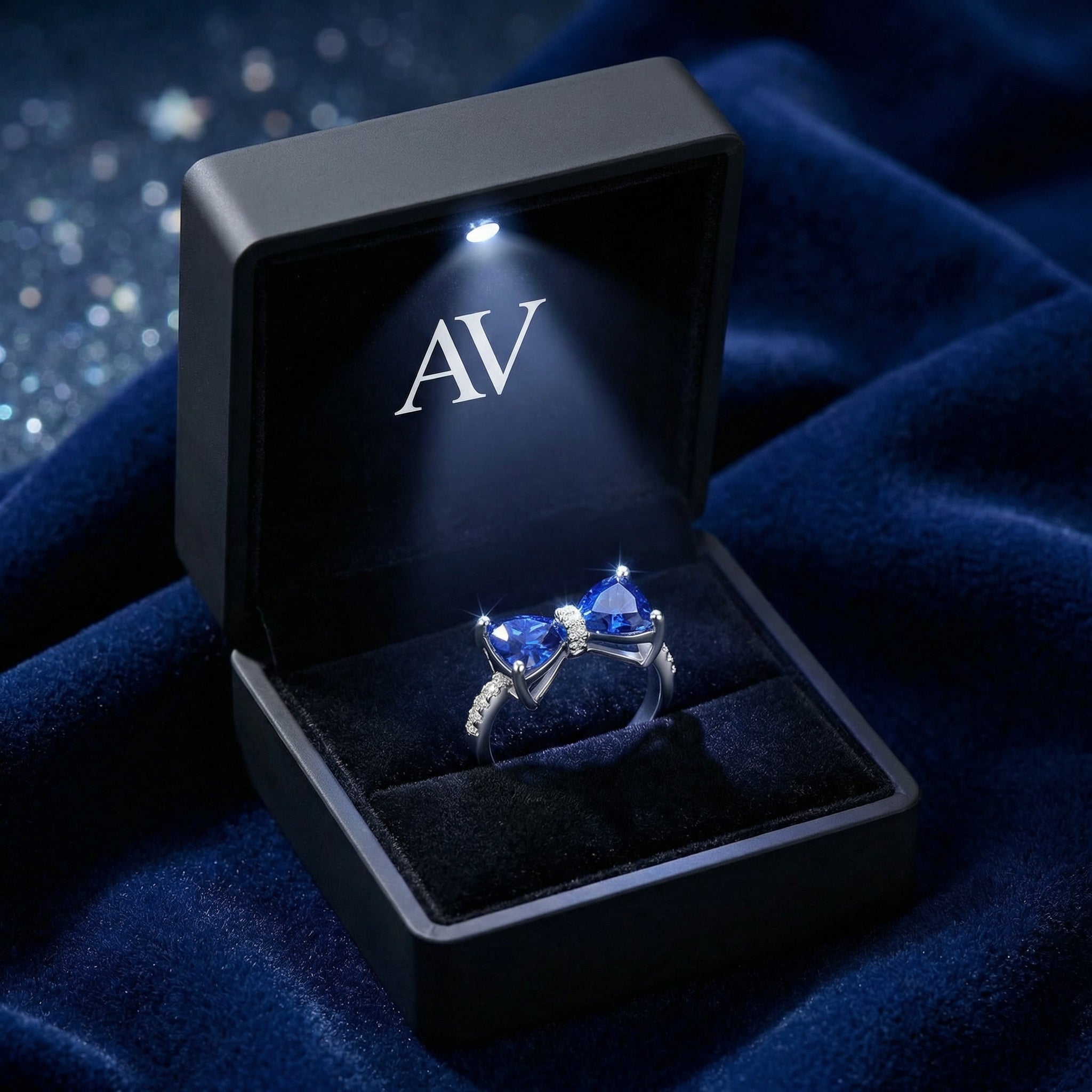 The S925 sterling silver Marcelle bow ring with blue simulated sapphires inside a black LED-lit gift box.