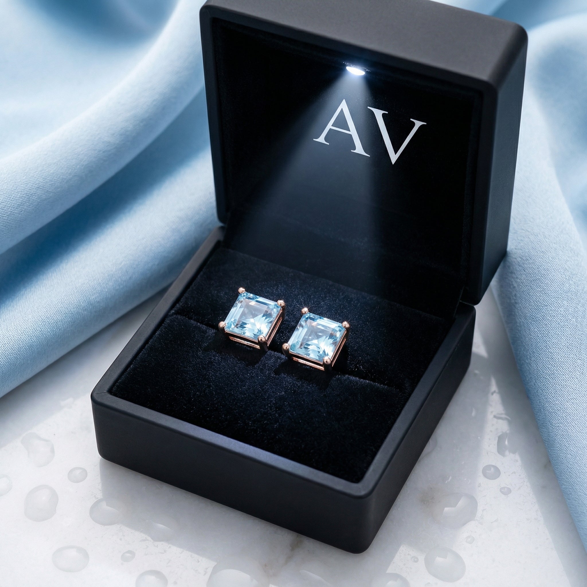 Princess cut simulated aquamarine studs in 18k rose gold vermeil inside a black LED-lit jewelry box.