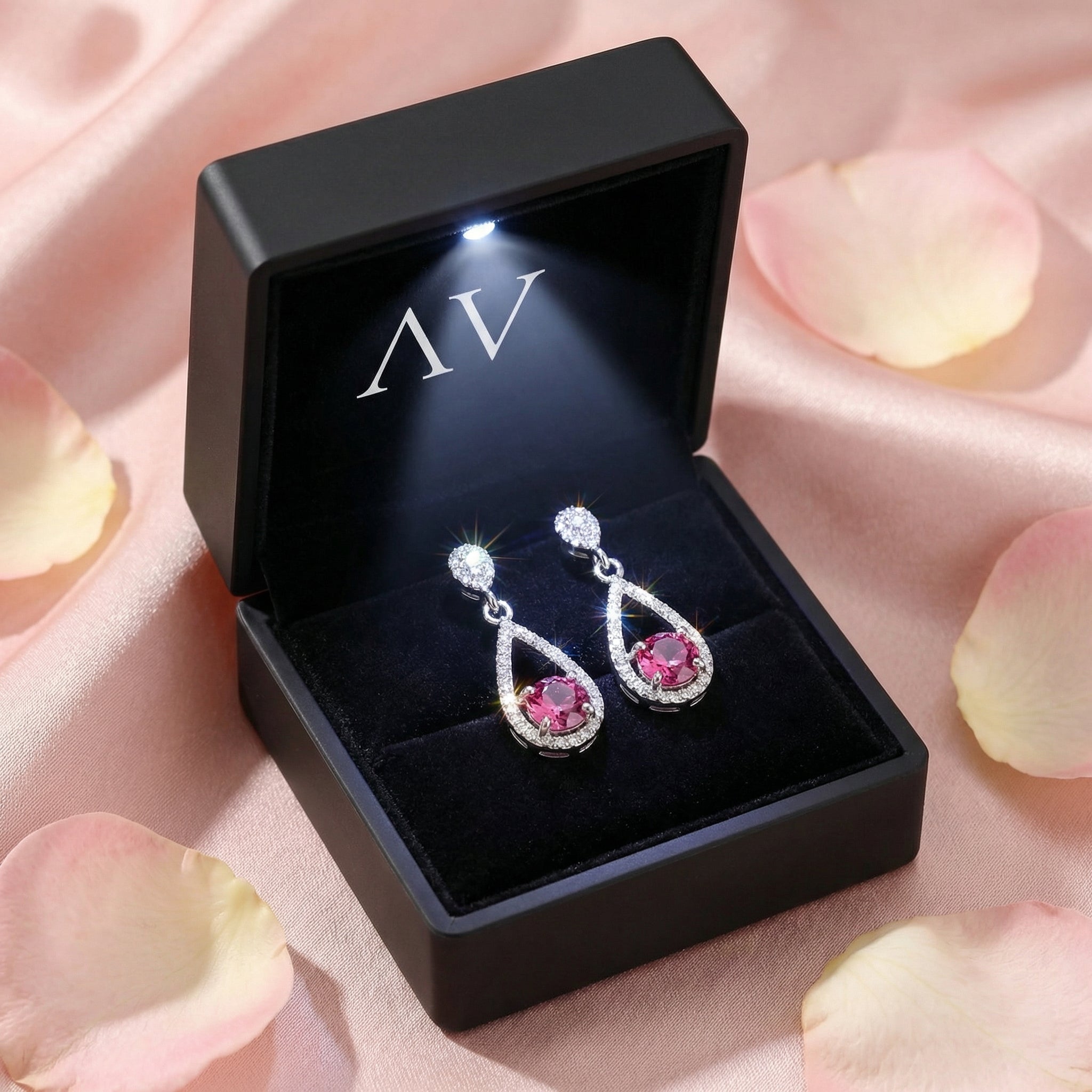 Pink tourmaline silver drop earrings in a black LED-lit jewelry box on a pink satin background.