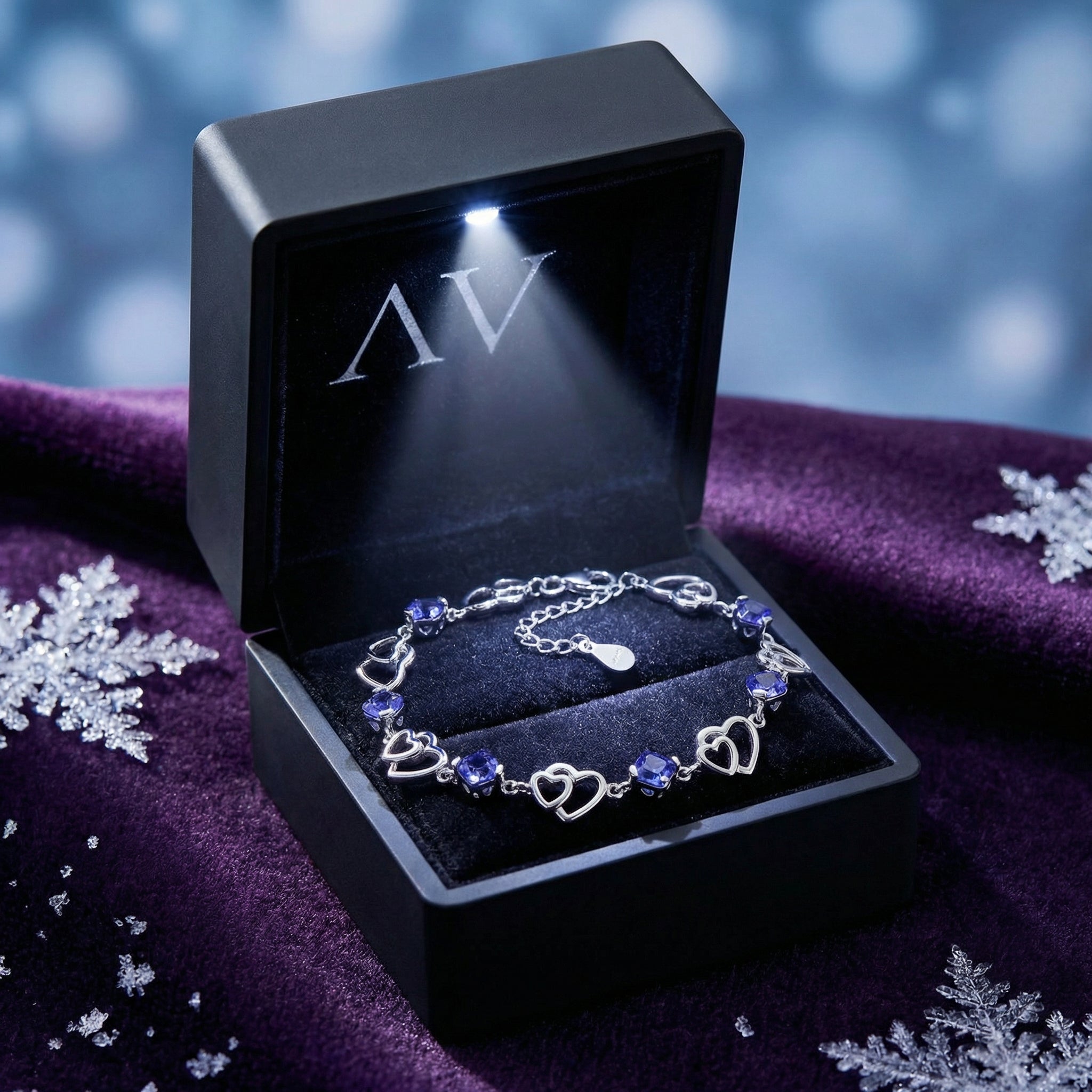 S925 sterling silver heart-linked bracelet with blue simulated tanzanite stones in a lighted black jewelry gift box.