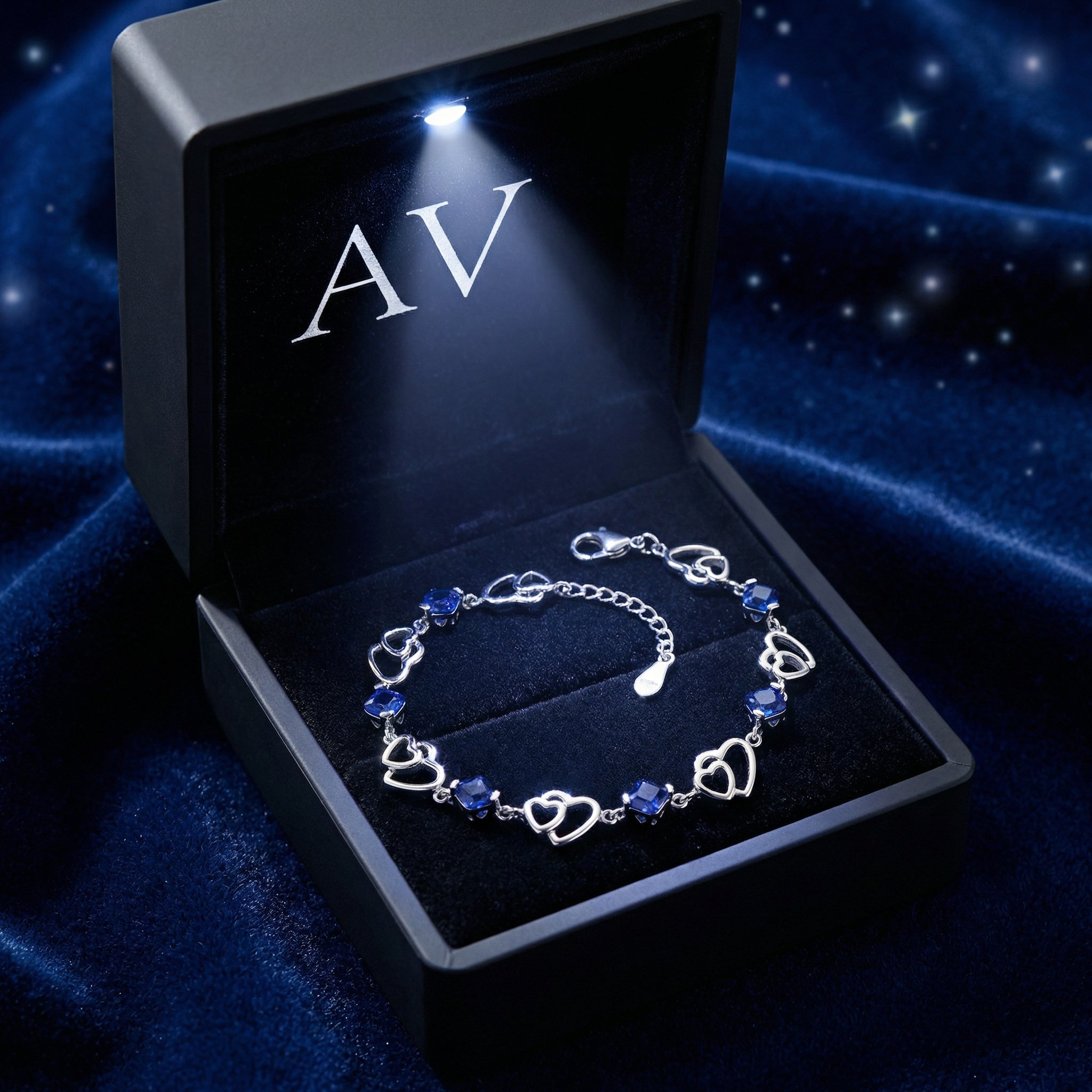 S925 sterling silver Celestelle heart bracelet with blue simulated sapphires in an LED-lit box on blue velvet.
