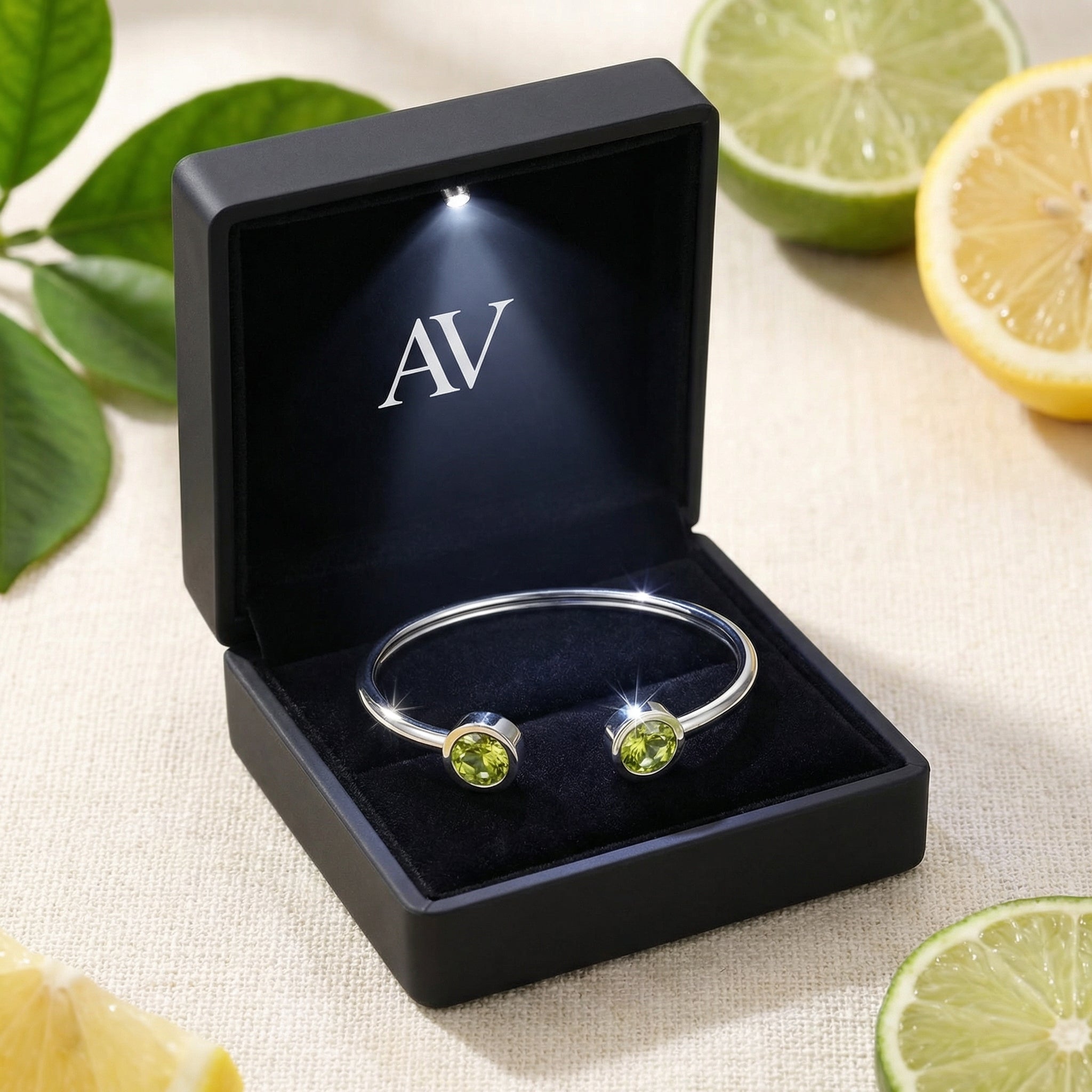 Silver stainless steel Peridara cuff bracelet with simulated peridots in a black LED-lit jewelry gift box.