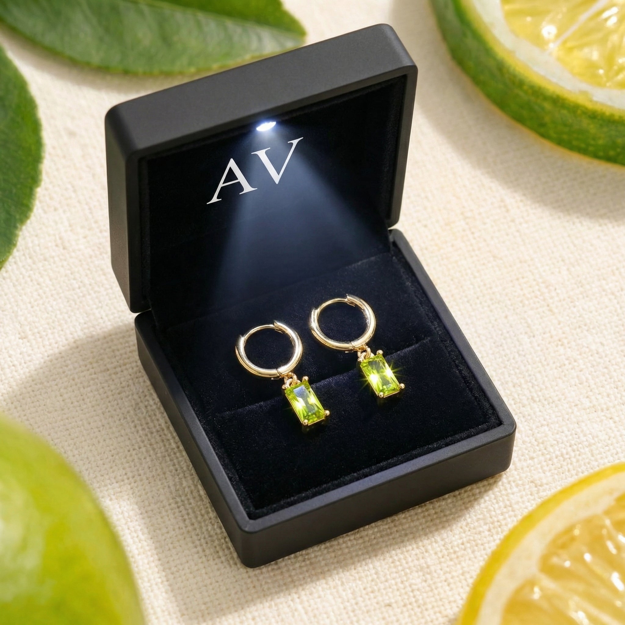 Gold vermeil Lunaris emerald-cut simulated peridot earrings presented in a black lighted jewelry gift box.