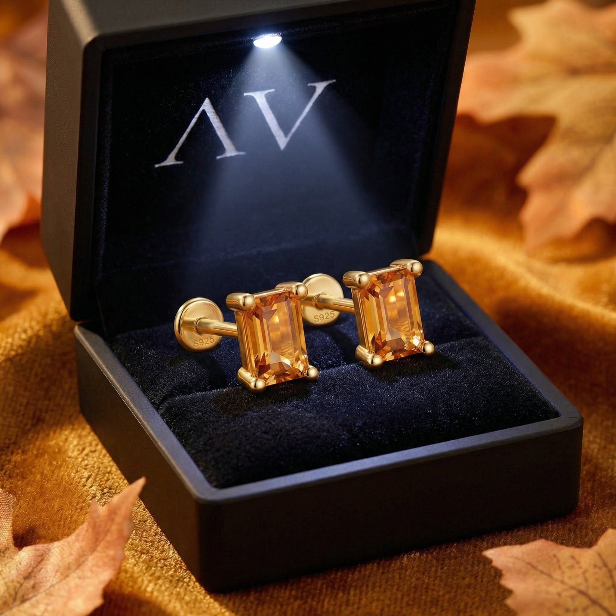 Pair of gold vermeil baguette simulated topaz earrings in a lighted black jewelry presentation box.