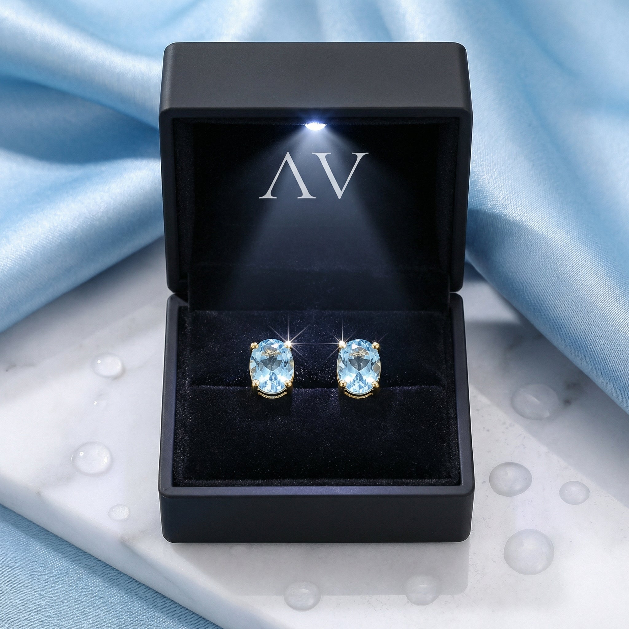 Oval cut simulated aquamarine gold vermeil earrings in a black LED-lit jewelry presentation box.