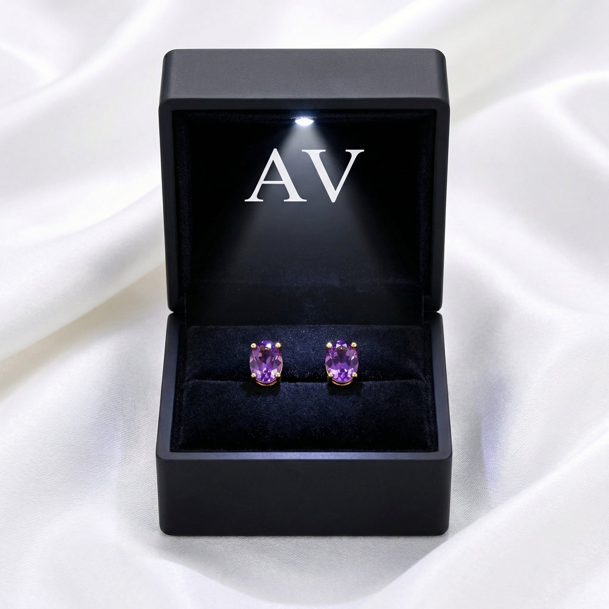 Oval simulated amethyst stud earrings in 18K gold vermeil inside a lighted black jewelry box.