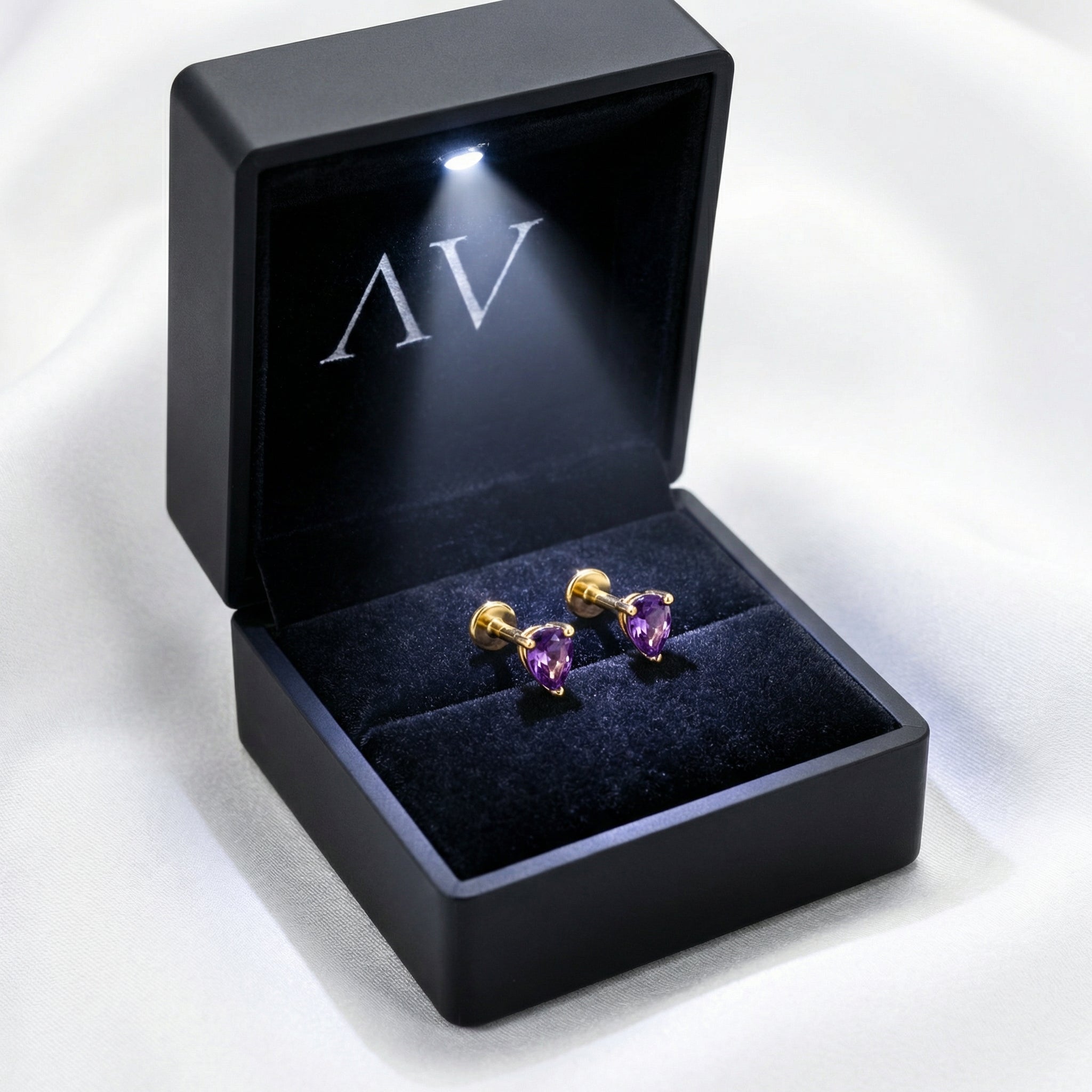 February birthstone simulated amethyst gold vermeil studs presented in a black lighted jewelry box.