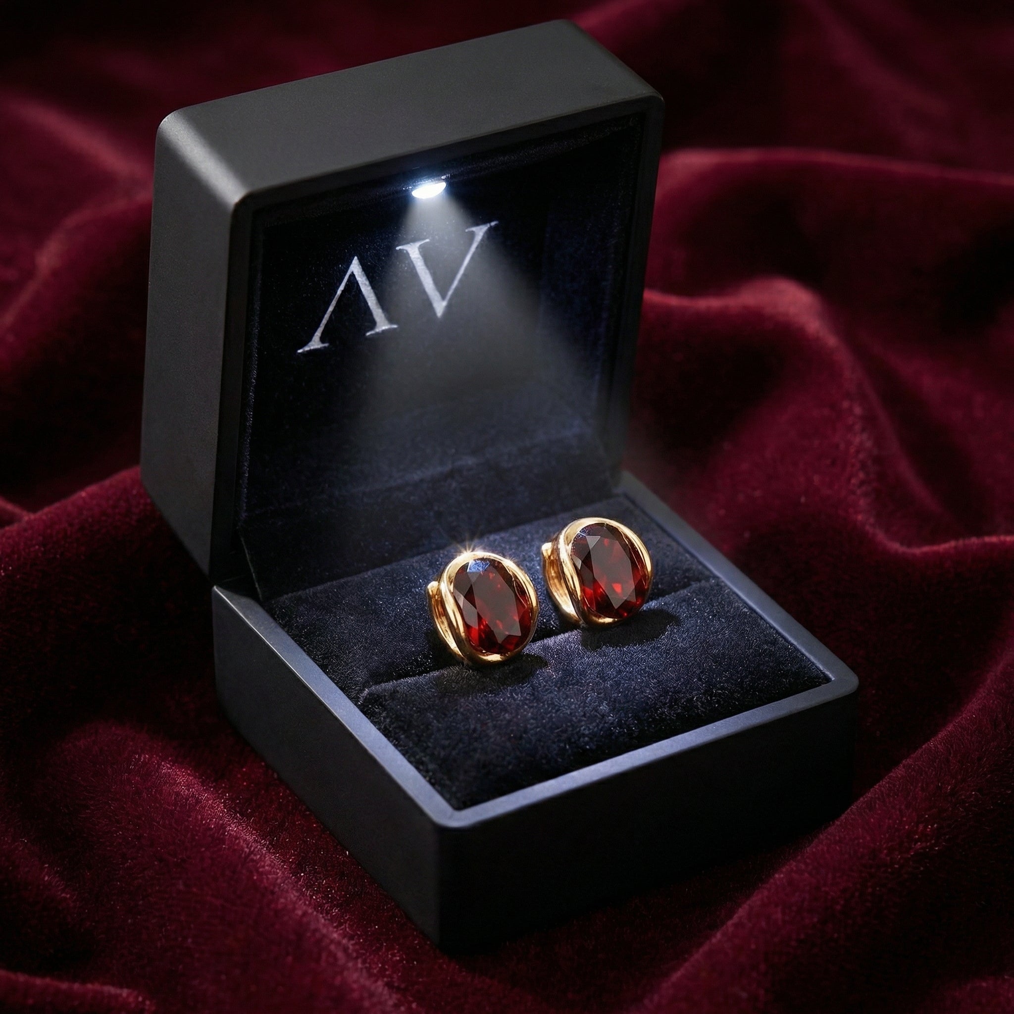 18K gold vermeil simulated garnet huggie earrings presented in a black LED-lit gift box on red velvet.