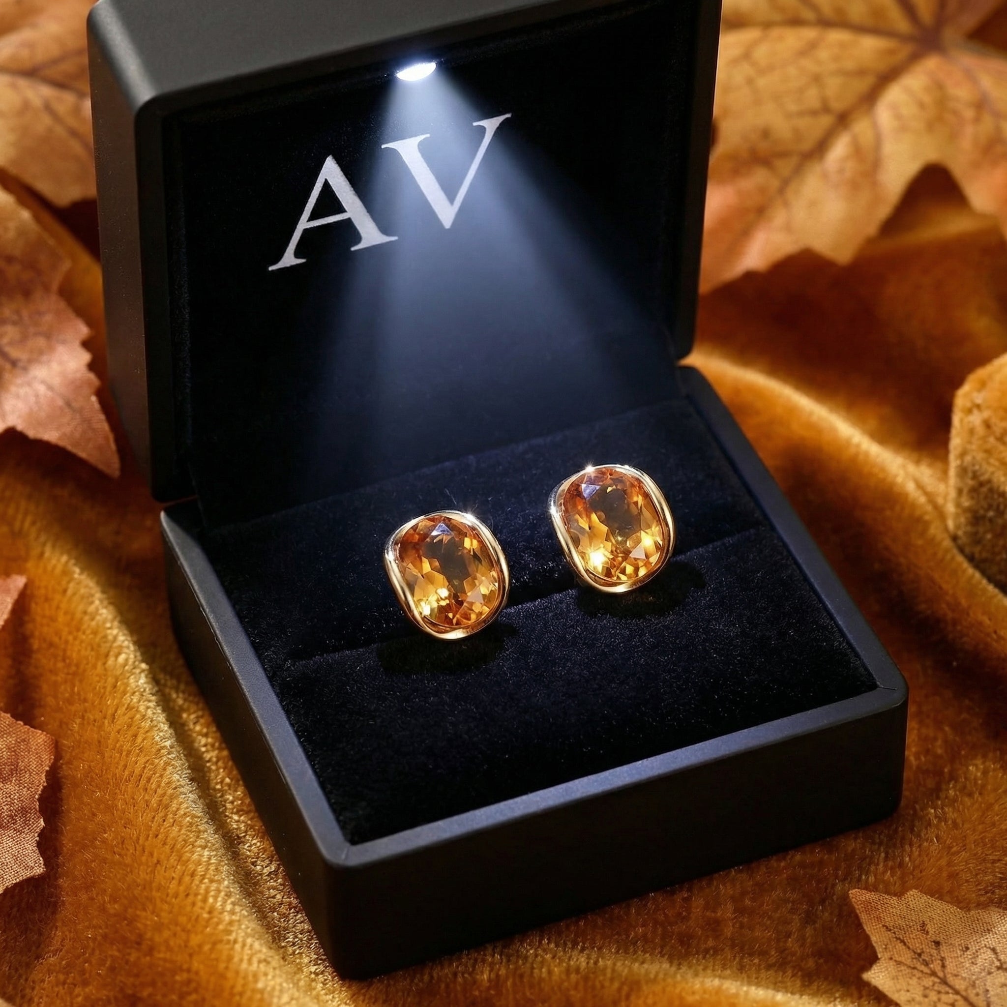 Oval honeyed simulated topaz stud earrings in 18K gold vermeil inside a lighted black AV branded gift box.