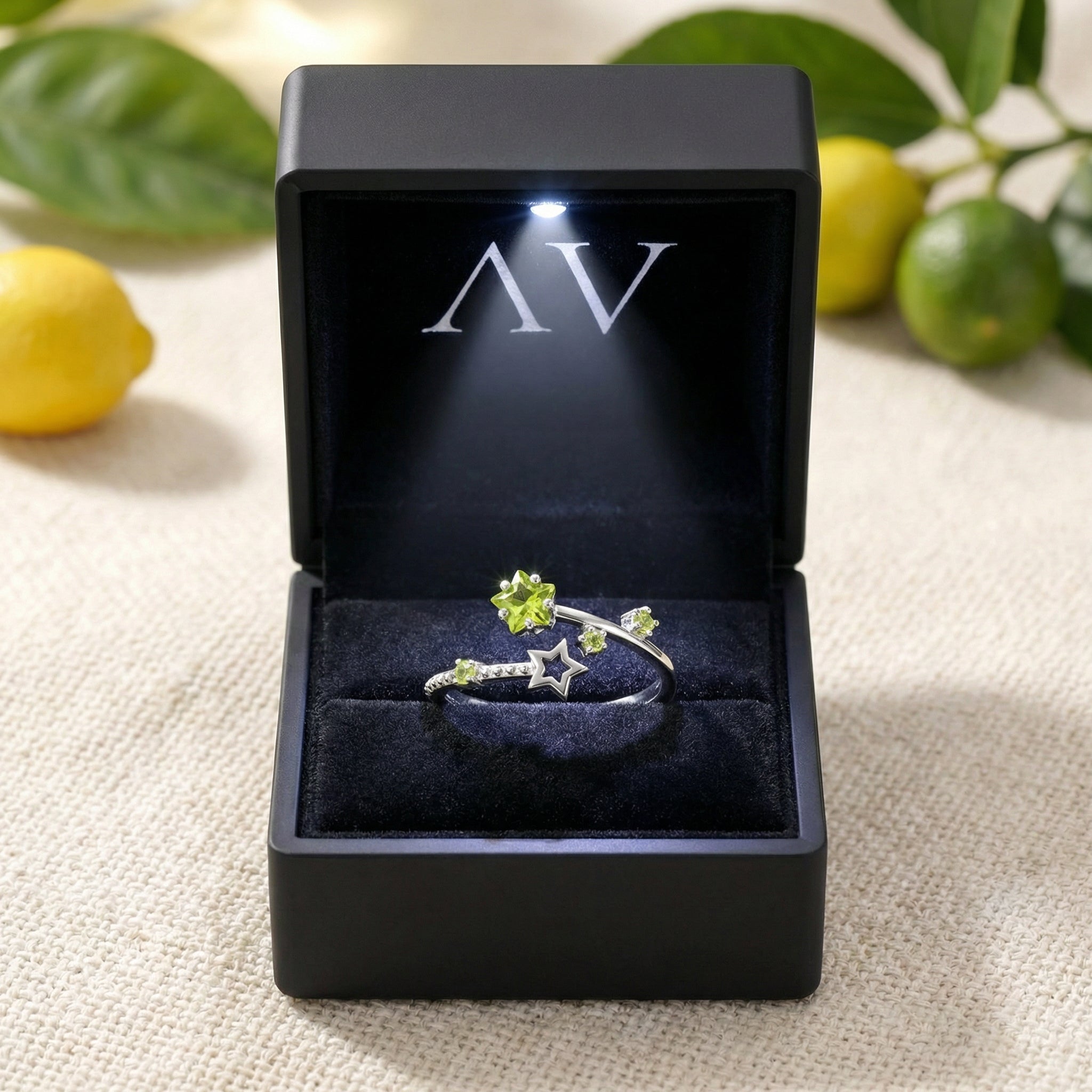 Stellina star bypass ring with simulated peridot stones inside a black LED-lit jewelry presentation box.