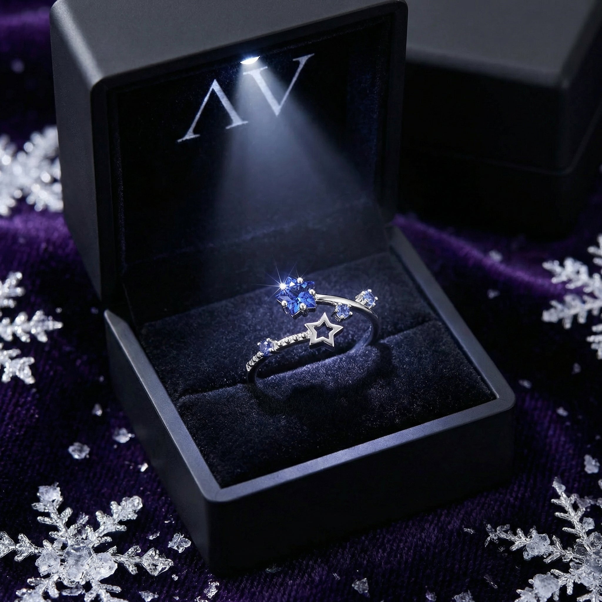 Sterling silver Nova Stellar ring with blue simulated tanzanite stars inside a lighted black jewelry gift box.