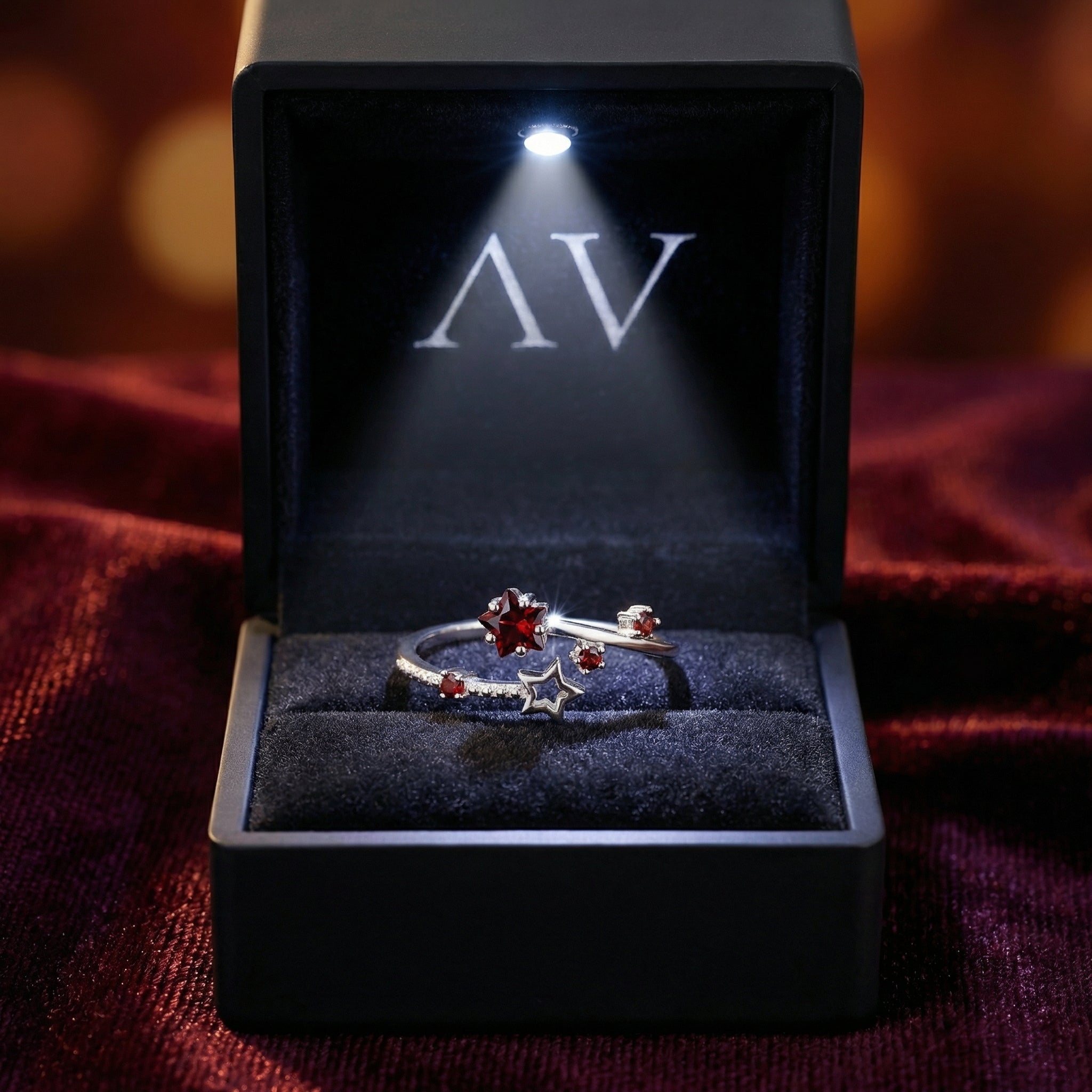 Sterling silver Sidereal Star Ring with red simulated garnets in a lighted black gift box.