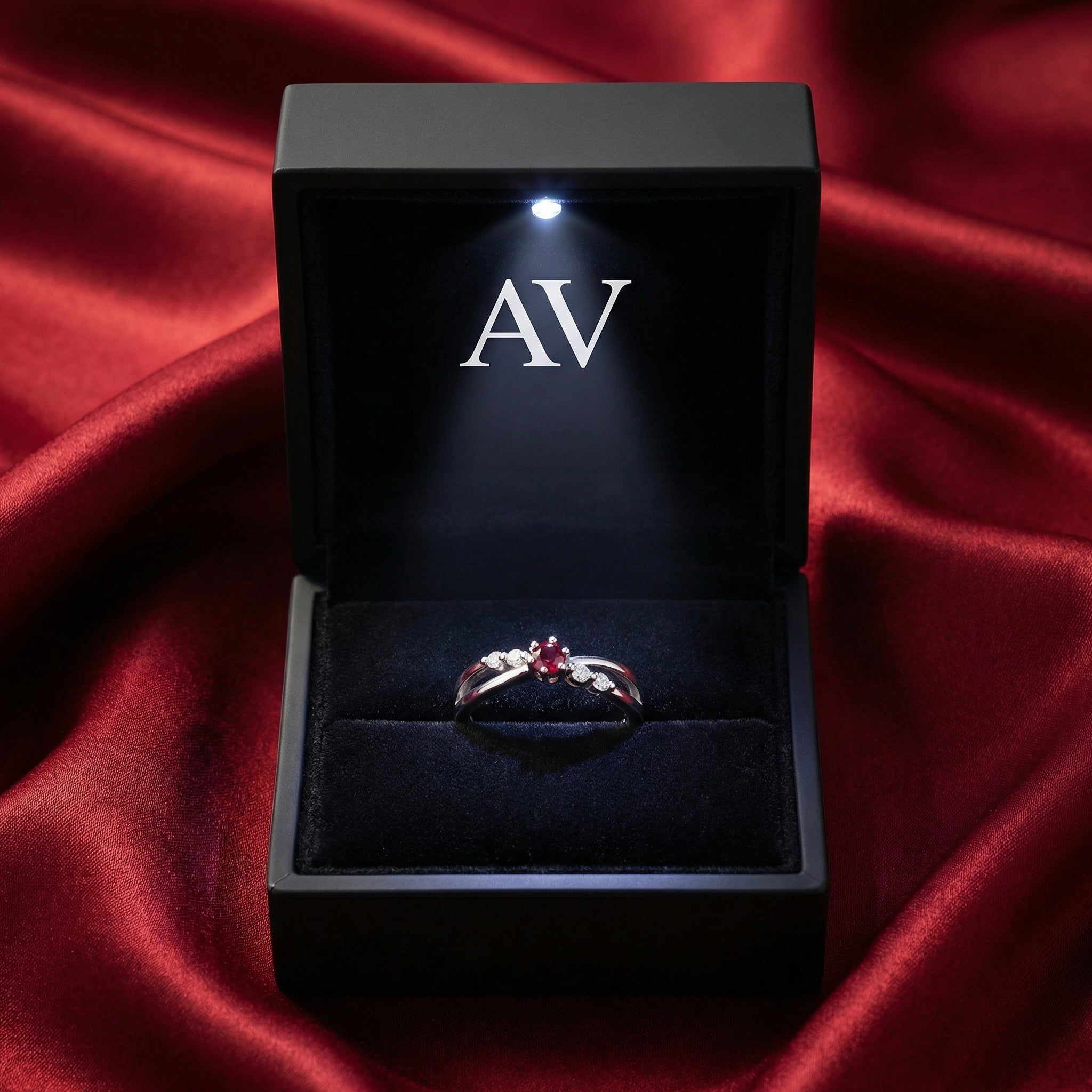 Round simulated ruby crossover ring in S925 sterling silver inside a black LED-lit gift box.