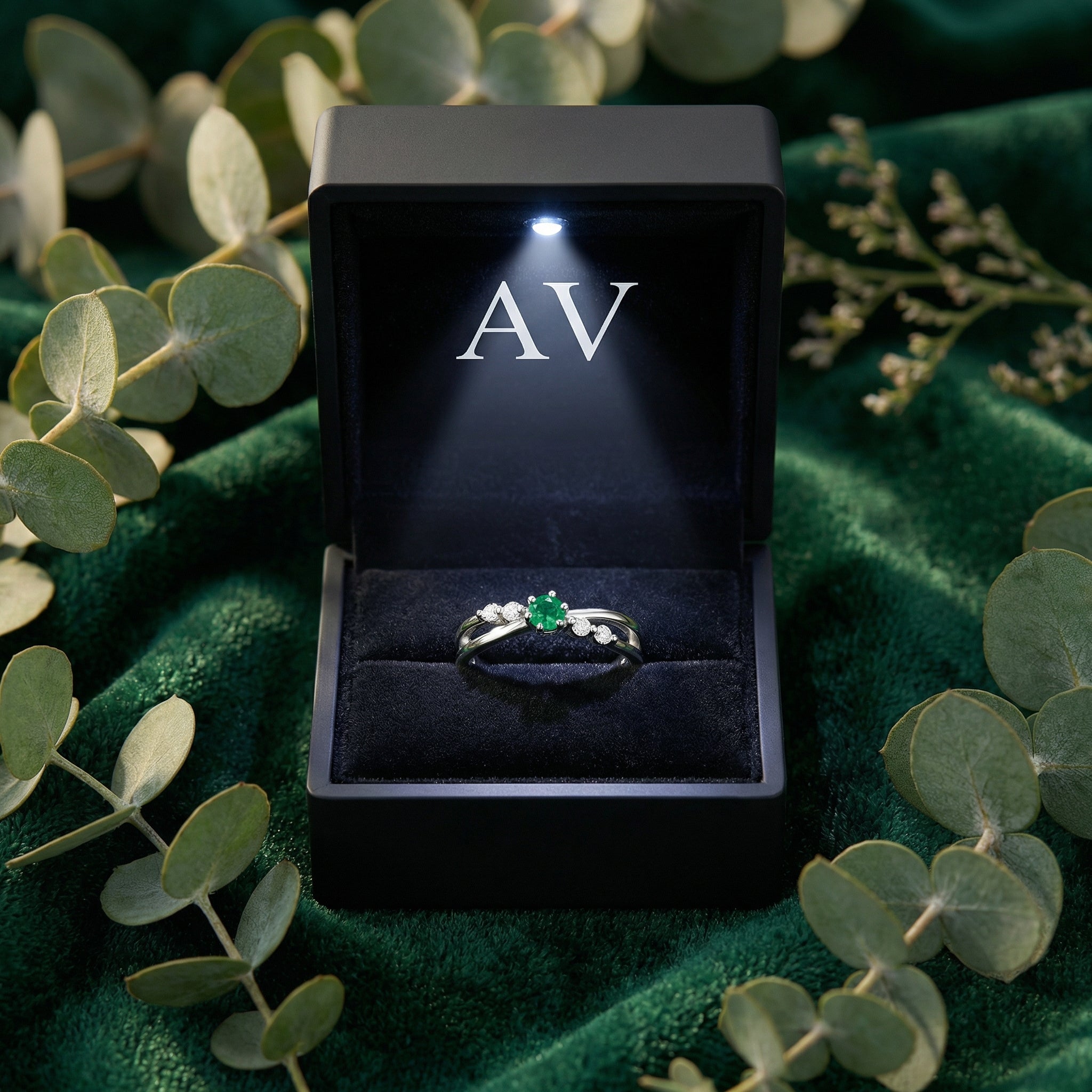 Sterling silver bypass ring with a simulated emerald in a black LED-lighted jewelry box.