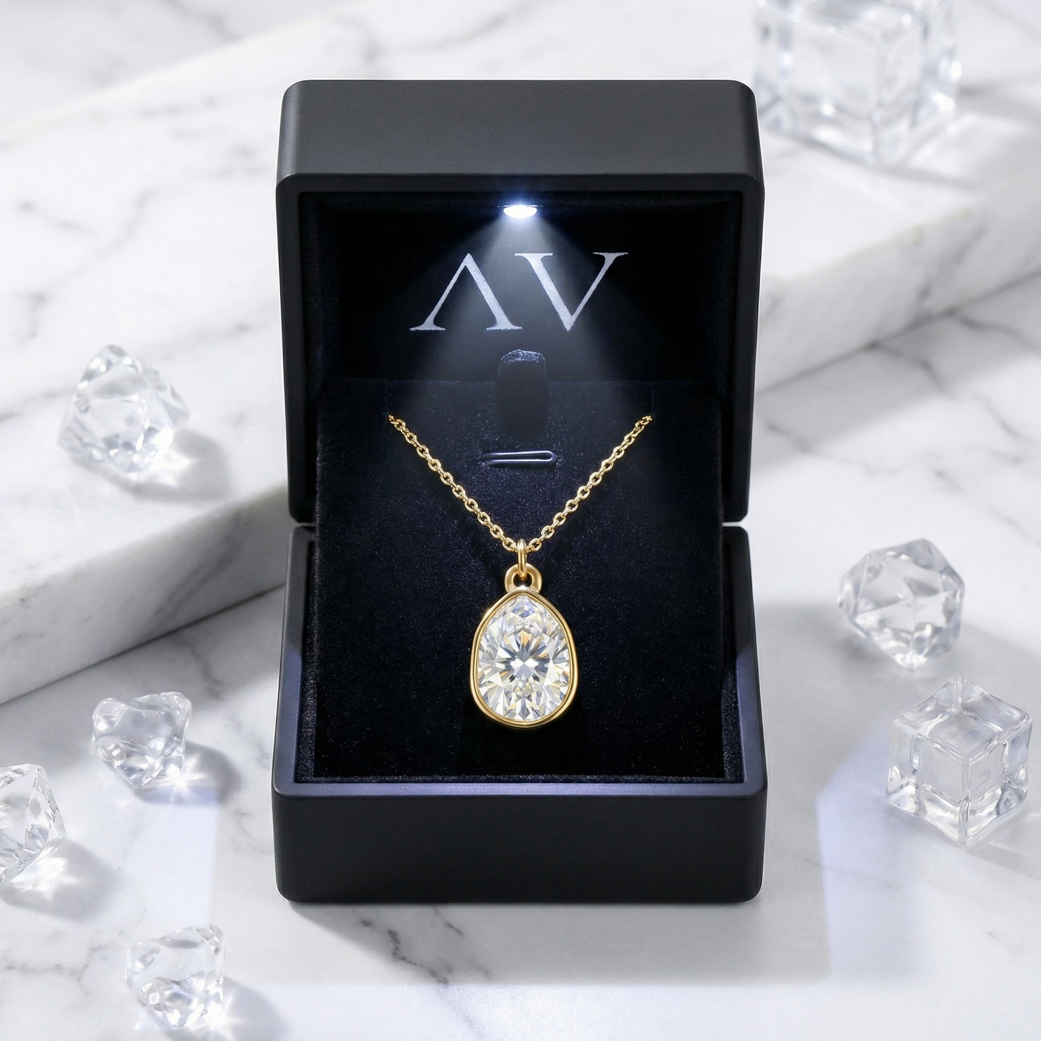 Pear-cut zirconia necklace in a gold-finished stainless steel setting inside a black lighted jewelry gift box.