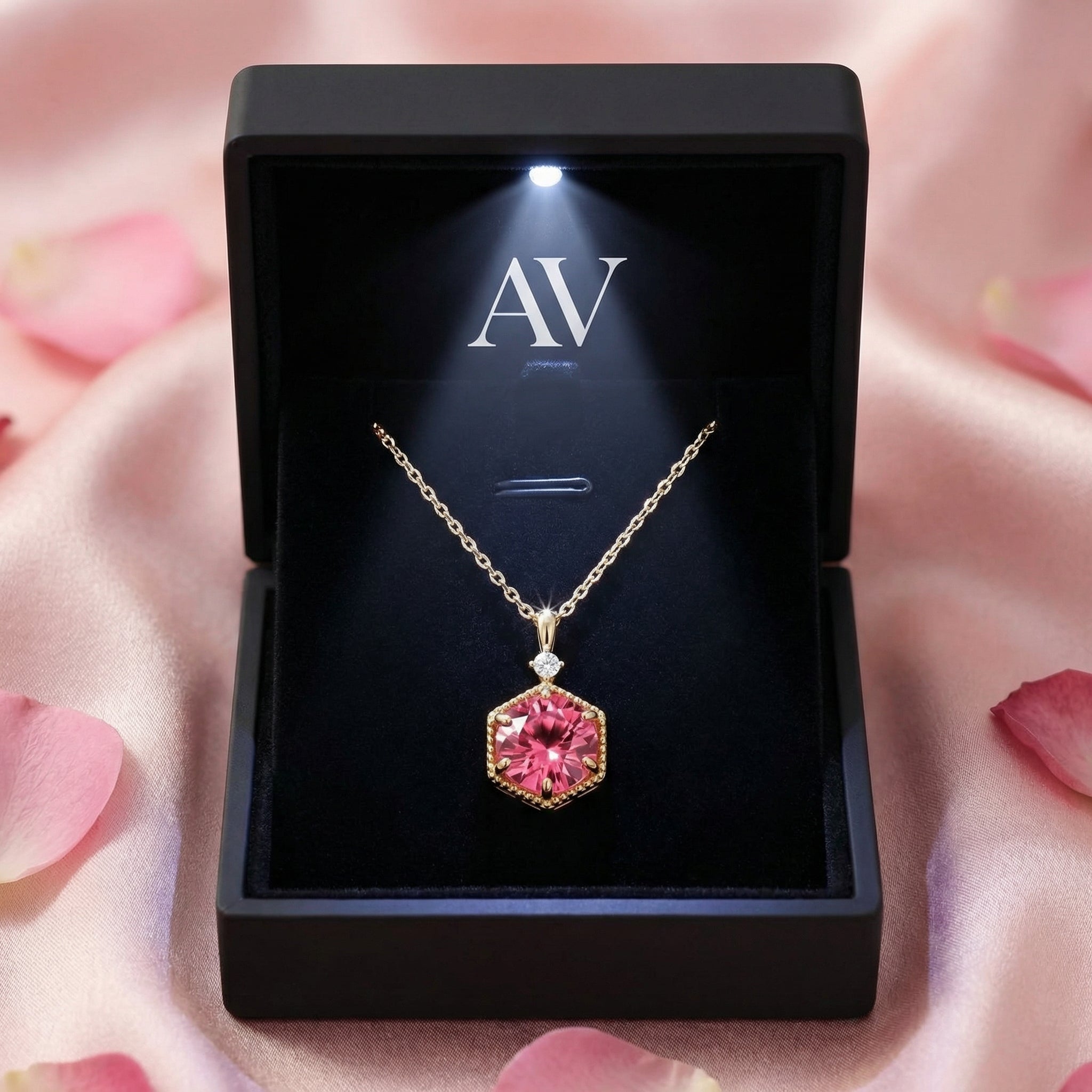Hexagonal pink tourmaline gold necklace inside a black LED-lighted jewelry box on pink silk.