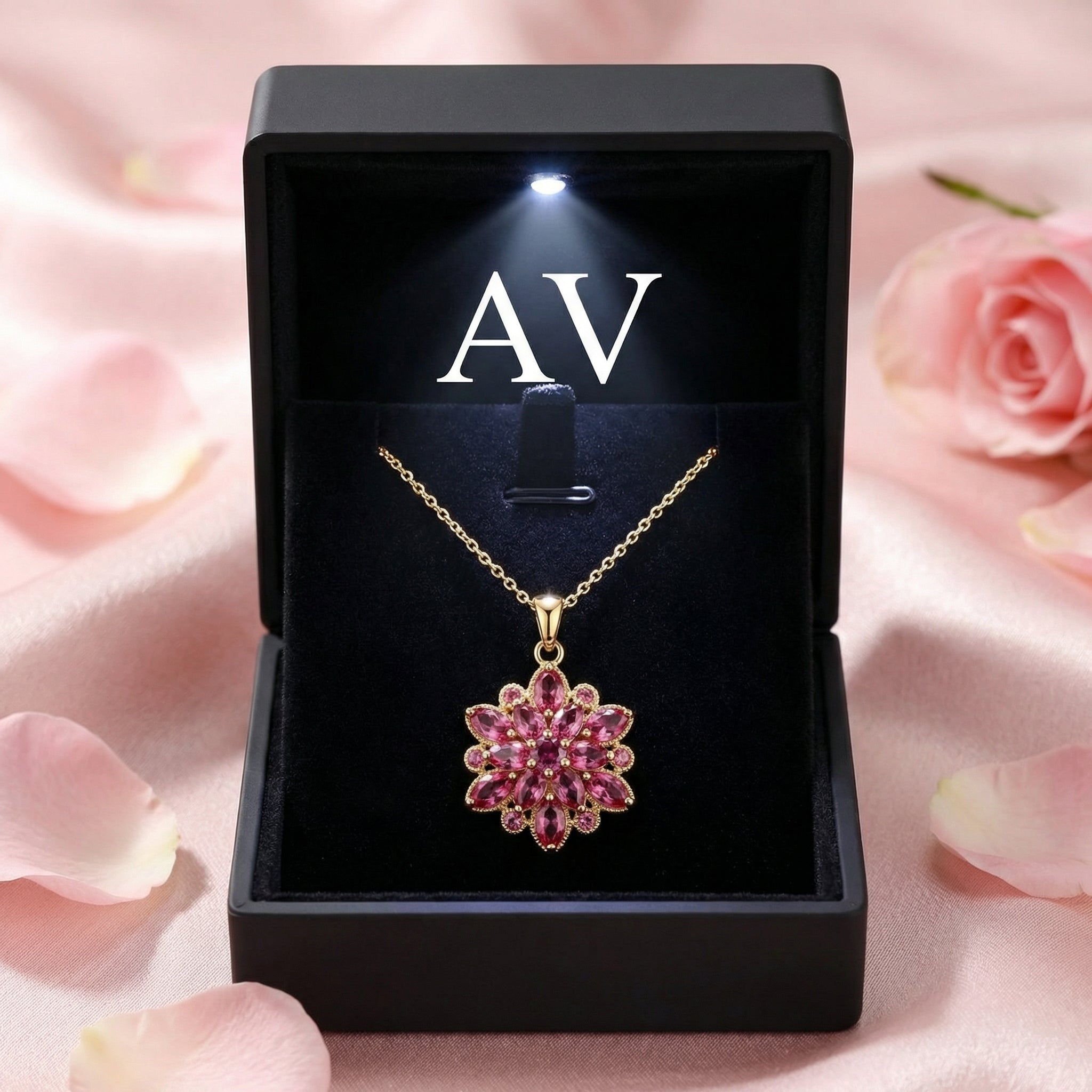 Gold finish Floralise pendant with pink stones inside a black LED-lit jewelry gift box with AV branding.