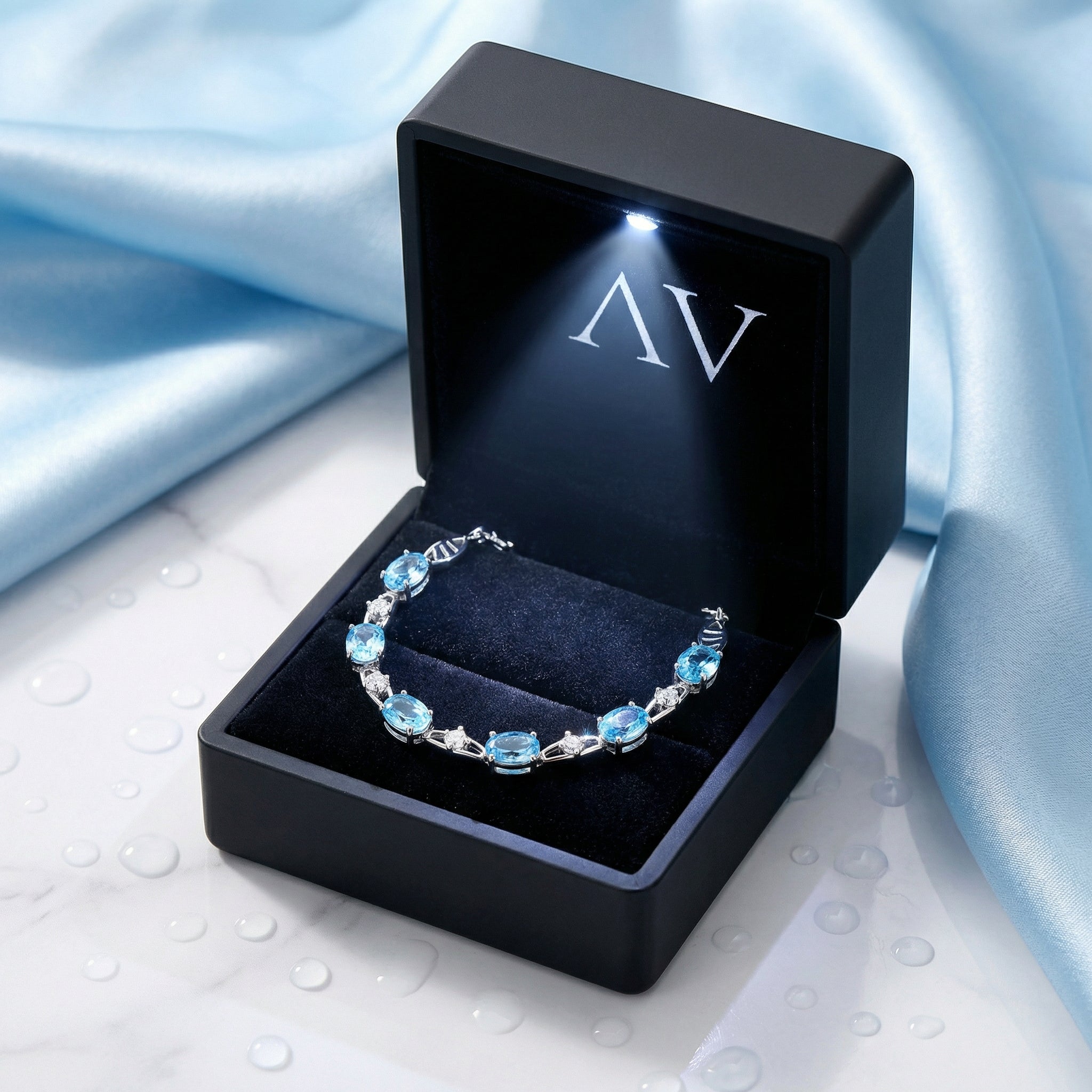 Oval cut simulated aquamarine sterling silver bracelet inside a black LED-lit presentation gift box.