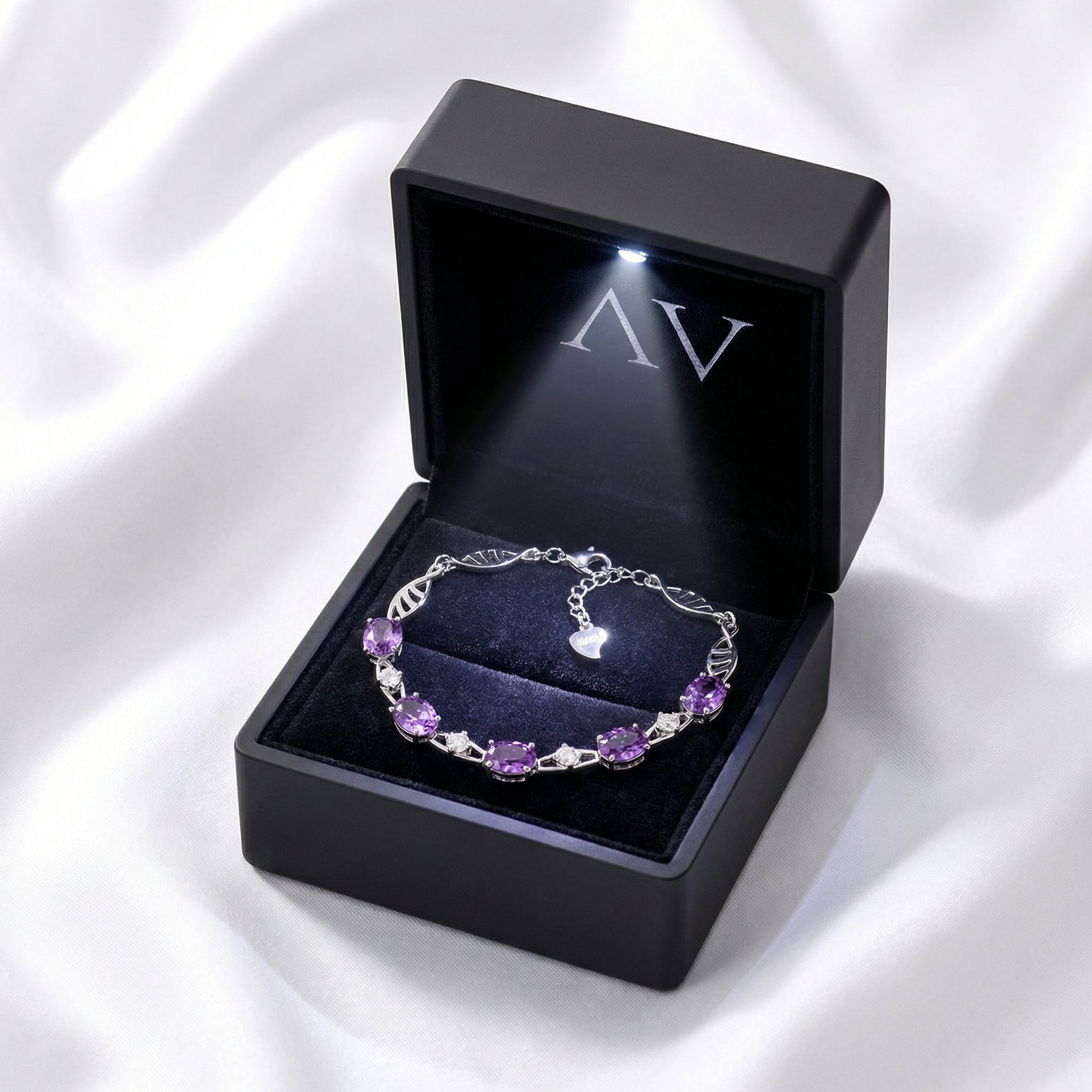 Sterling silver amethyst link bracelet presented in a black LED-lighted gift box on white satin fabric.