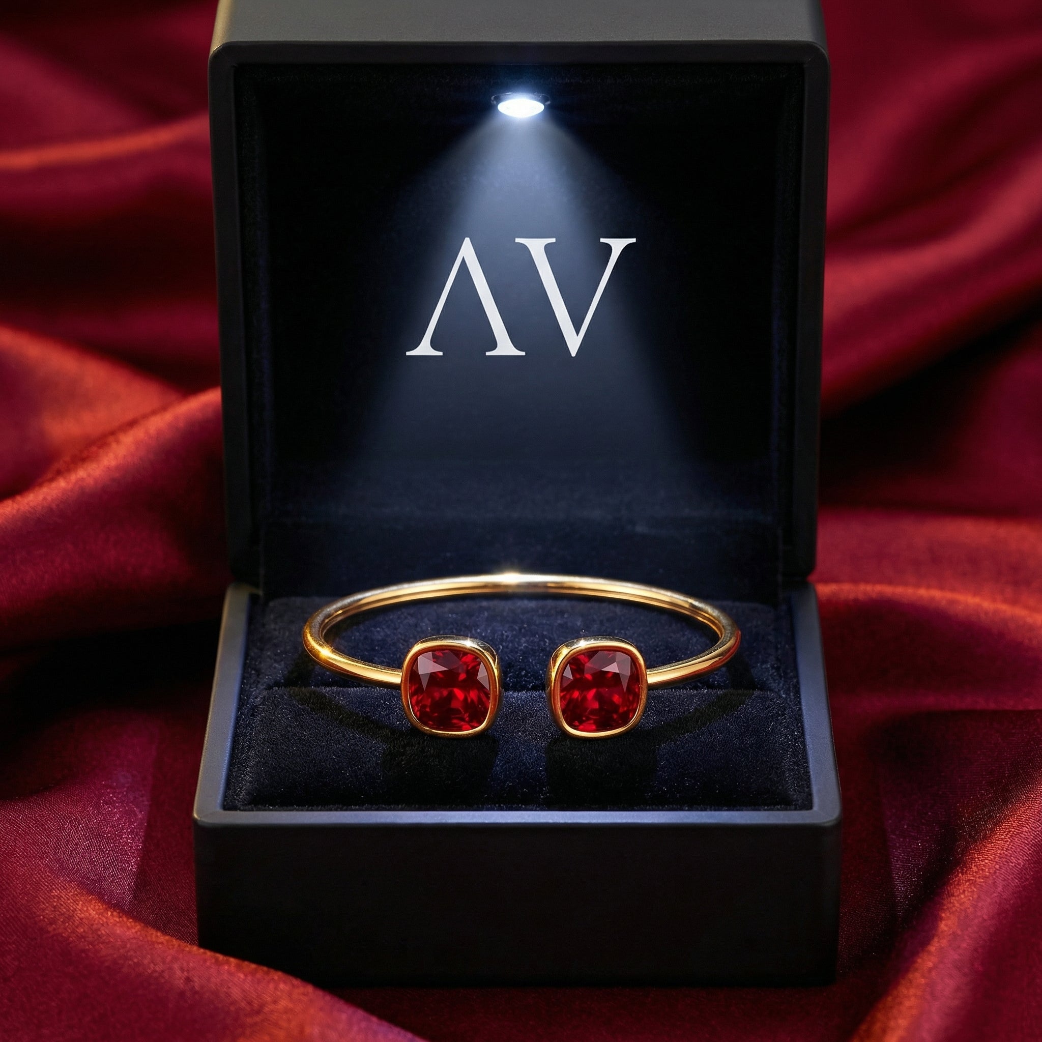 Gold-tone stainless steel cuff bracelet with red simulated rubies in a lighted black AV jewelry box.