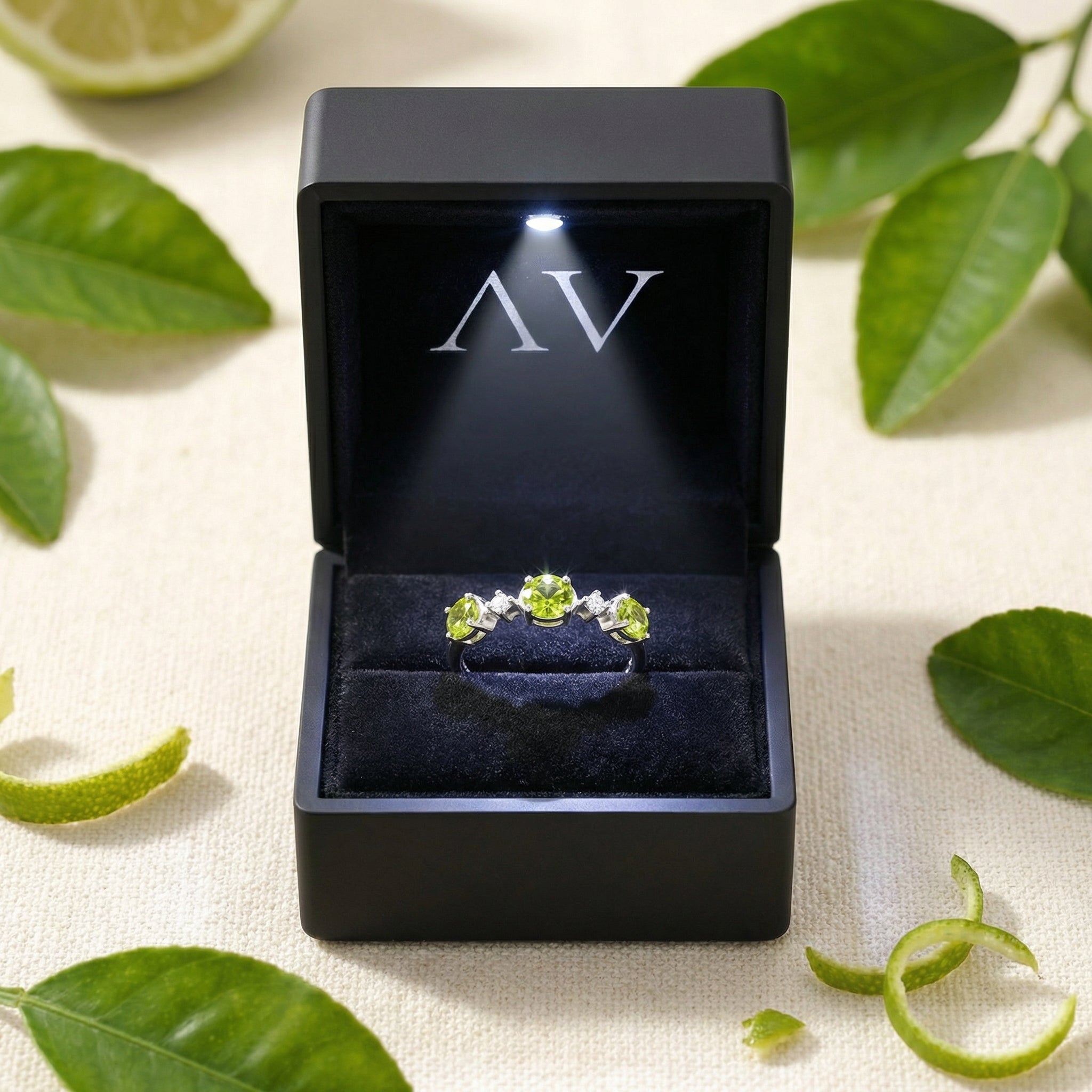 Mirabelle S925 sterling silver ring with green simulated peridots in a black LED-lit jewelry presentation box.