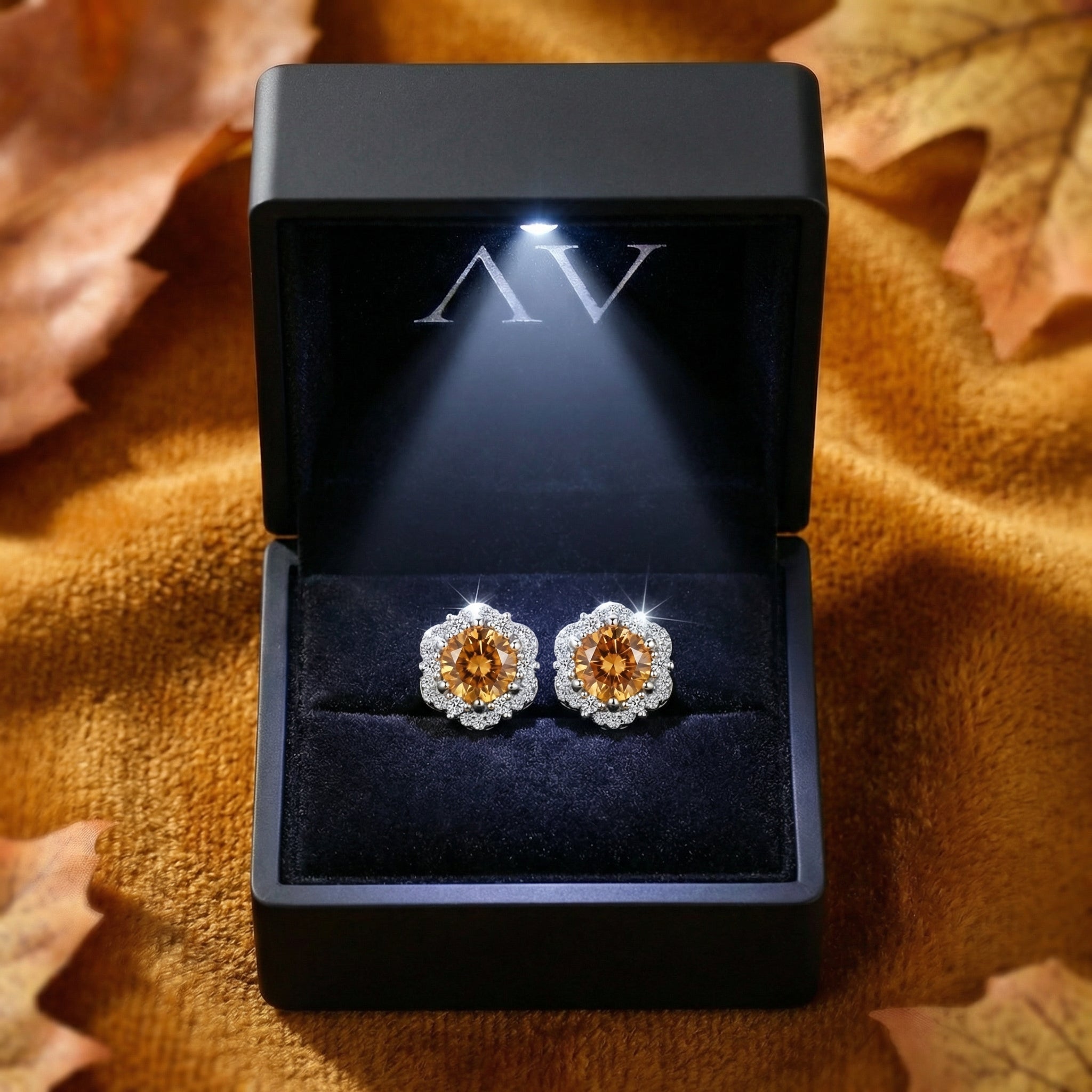 Sterling silver halo stud earrings with round simulated topaz stones inside a lighted black jewelry gift box.