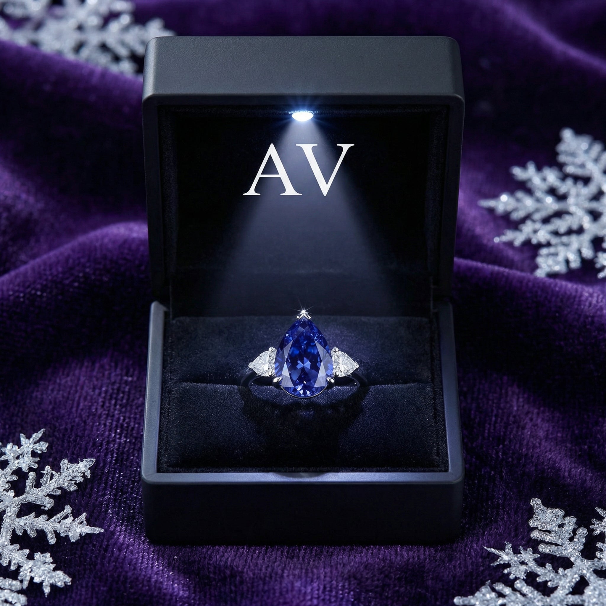 Pear-cut simulated tanzanite sterling silver ring inside a lighted black jewelry gift box.