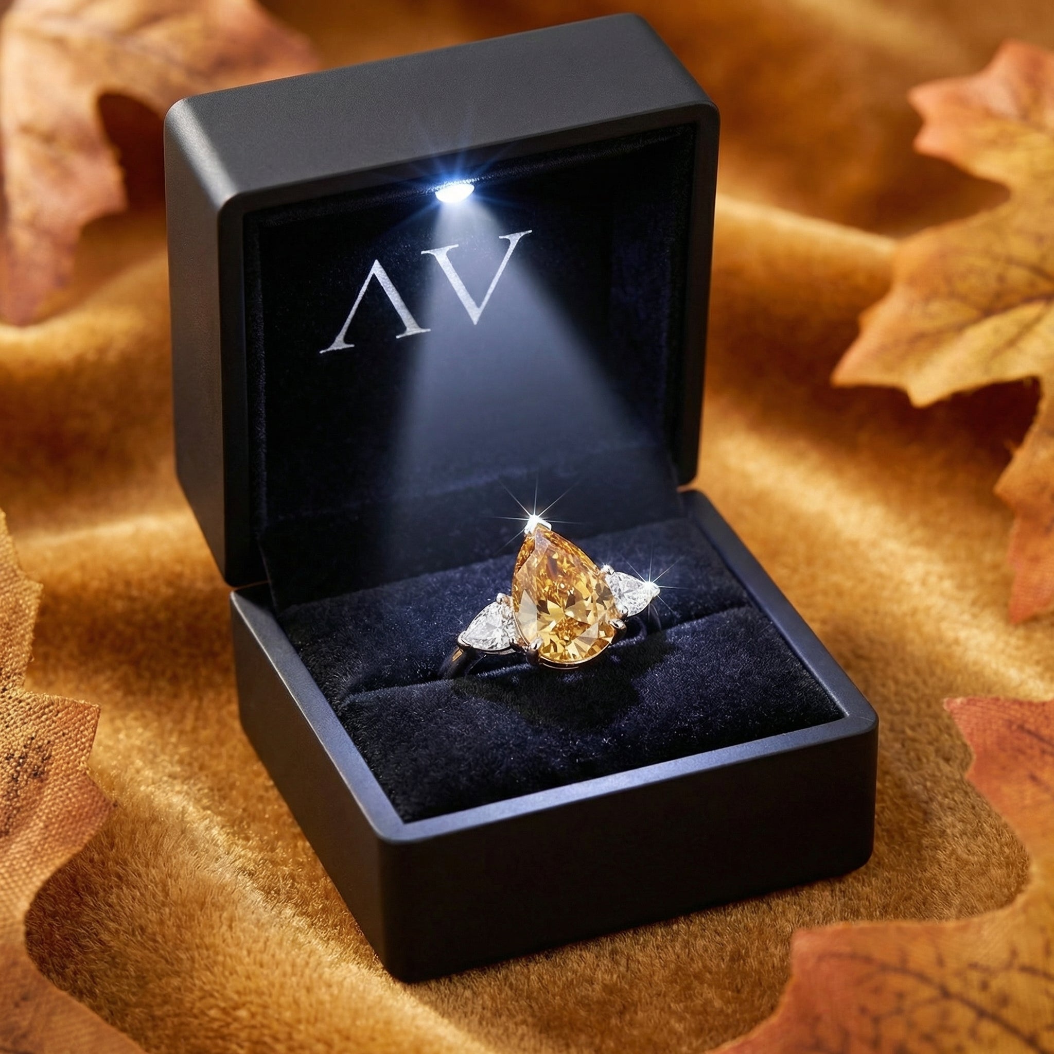 Pear-cut honey simulated topaz ring presented in a black lighted gift box with the AV logo.
