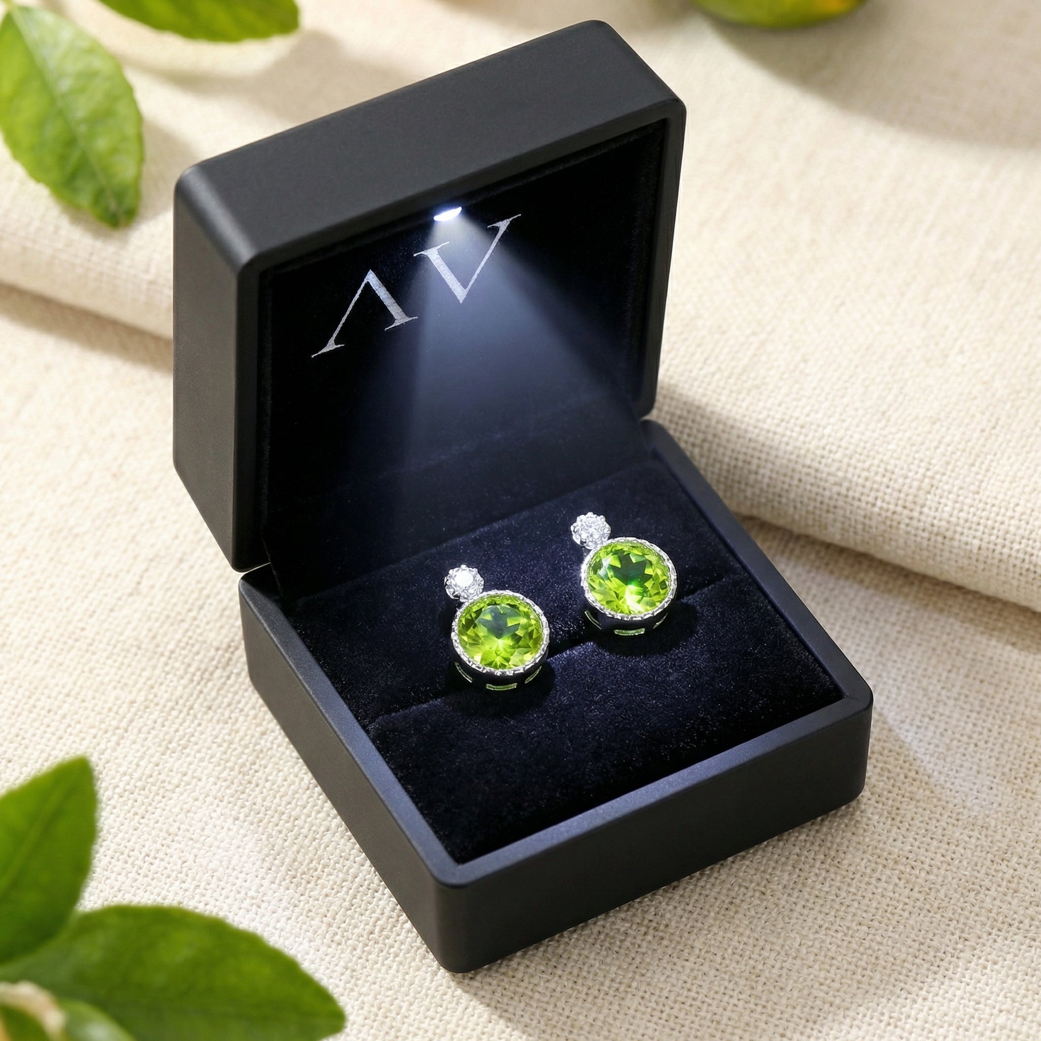 Pair of sterling silver peridot stud earrings inside a premium black LED-lighted jewelry gift box.