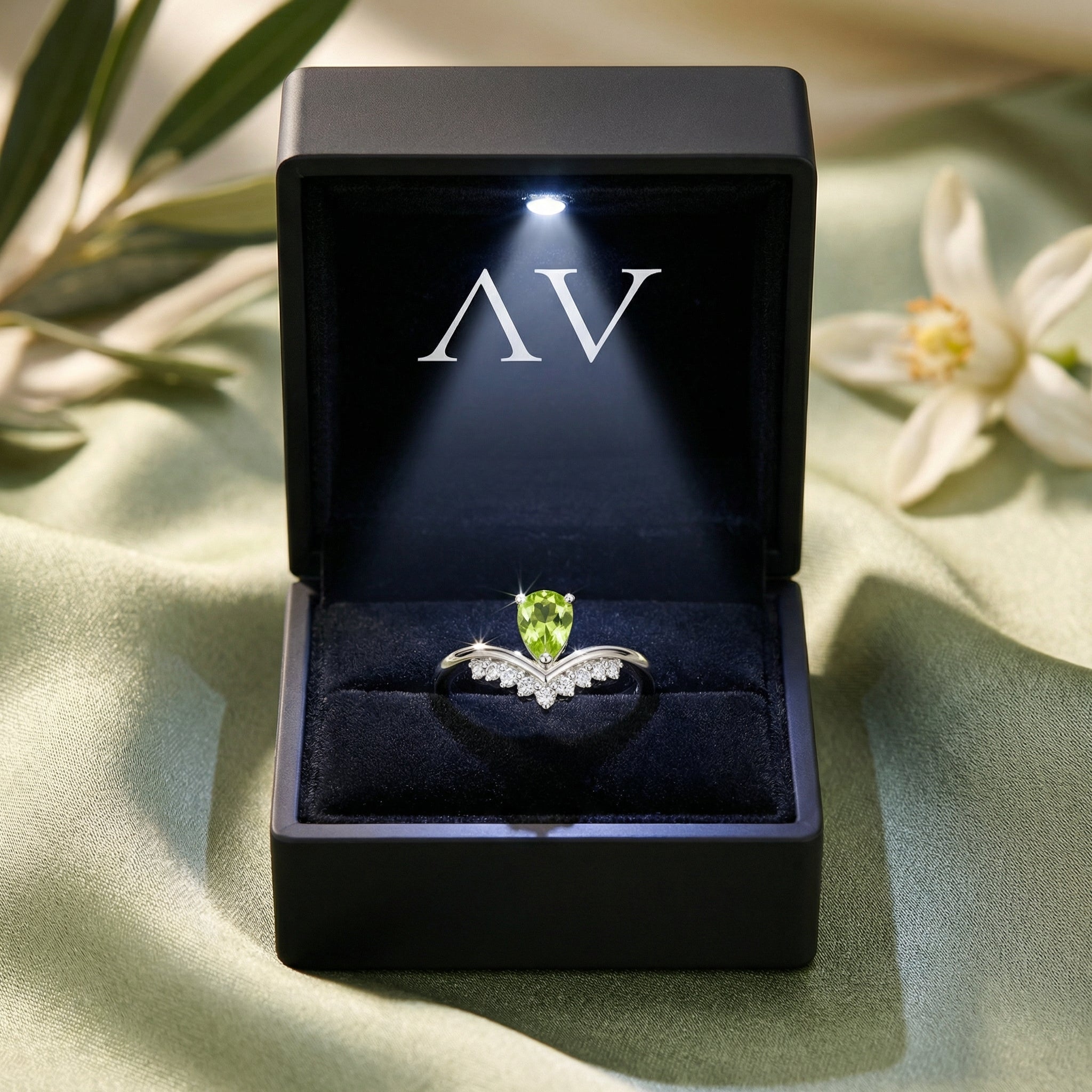 Natural pear cut peridot sterling silver ring presented in a black LED-lit jewelry box on green fabric.