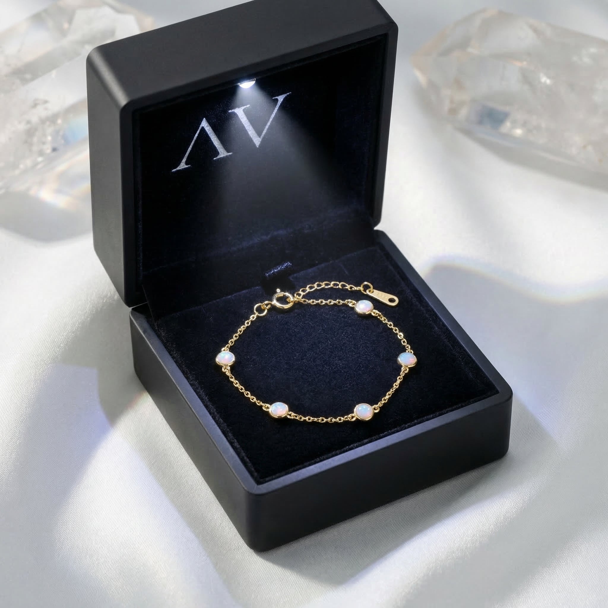 Gold round cut opal station bracelet presented in a luxury black light-up gift box on white silk.