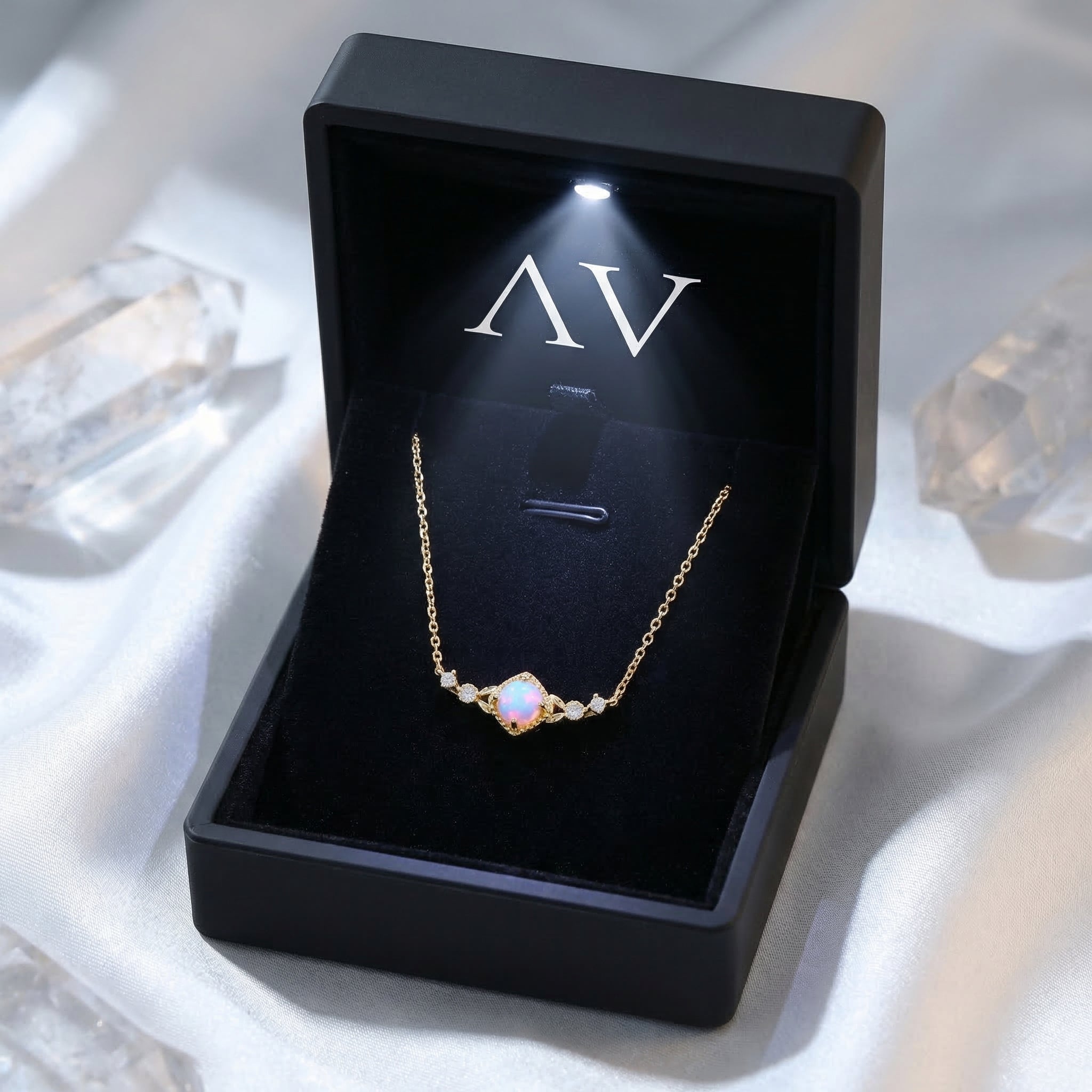 Gold-tone white opal necklace presented in a black lighted jewelry box with the AV logo.