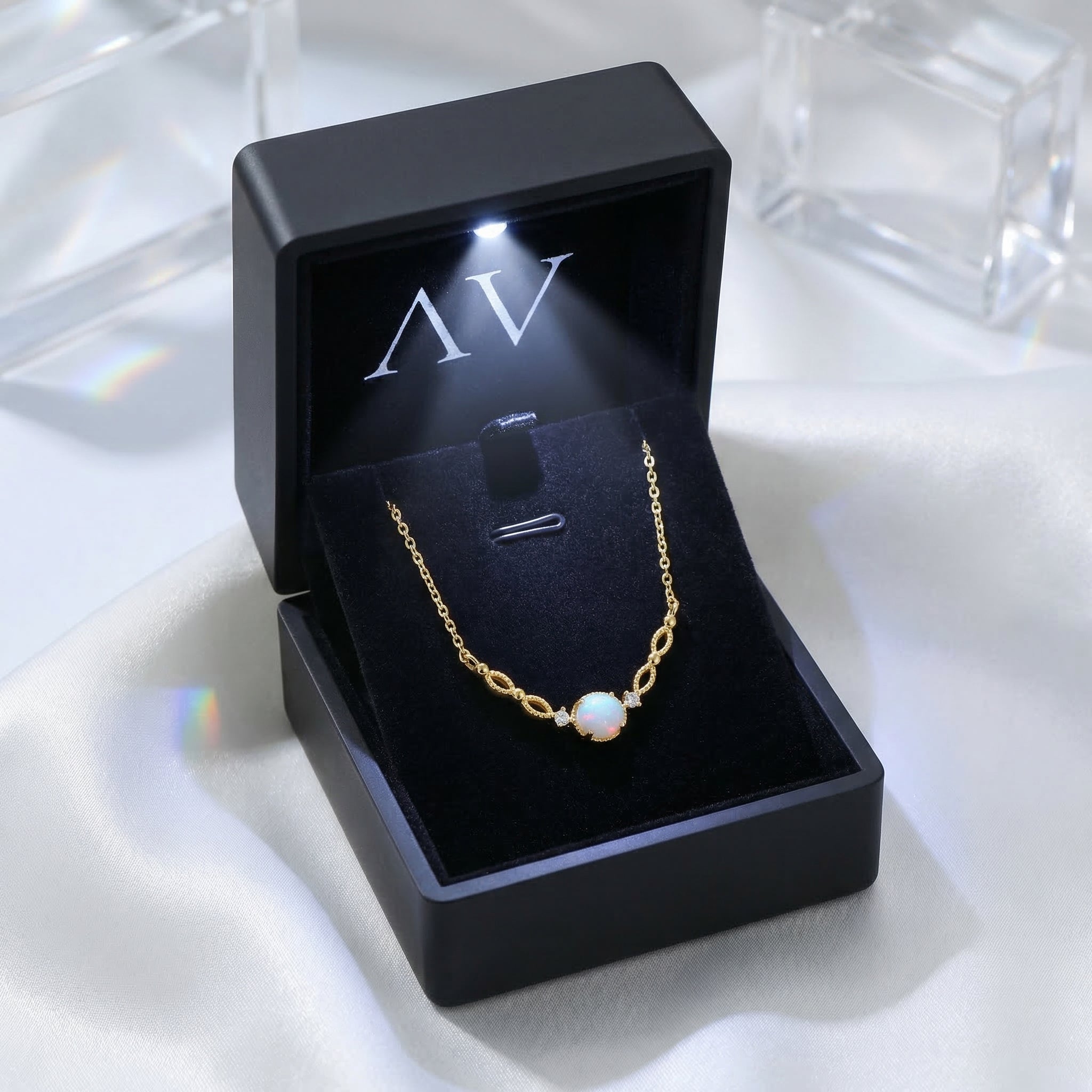 Gold-tone white opal pendant necklace presented in a lighted black jewelry gift box.