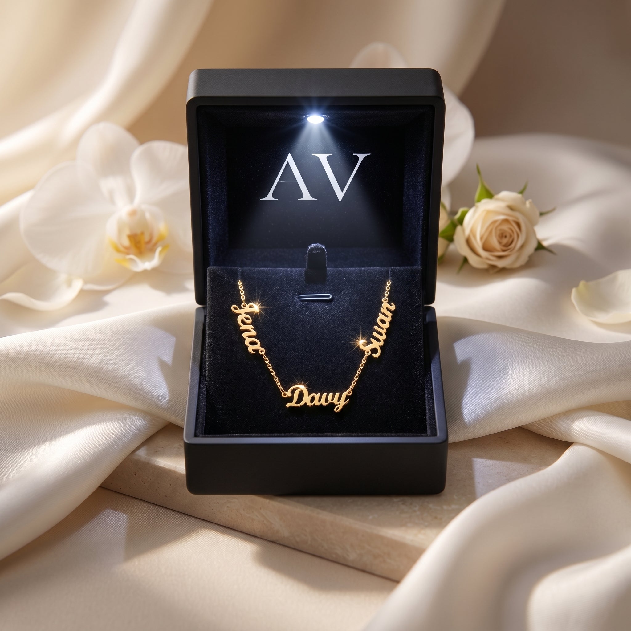 Gold PVD stainless steel name necklace in a black LED-lit presentation box.