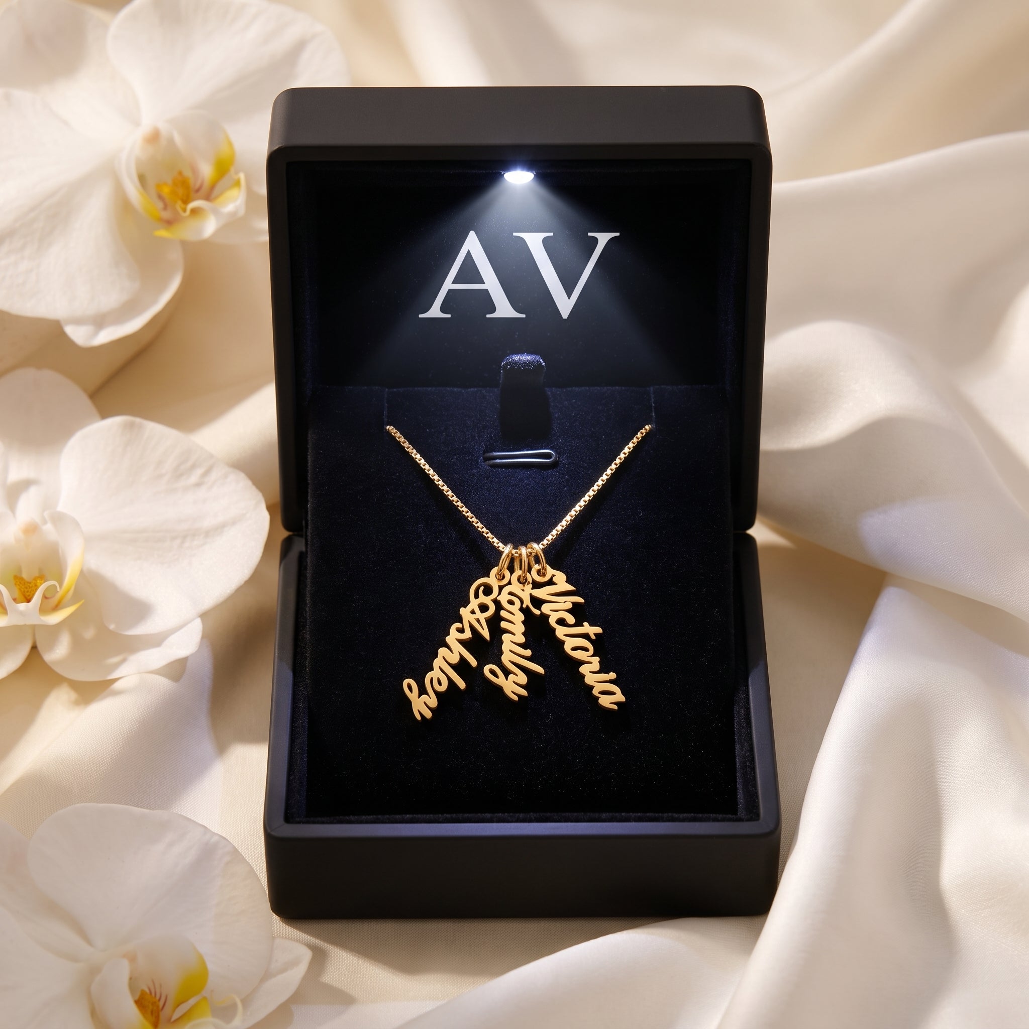 Gold name necklace in a black LED-lit gift box with white orchids.