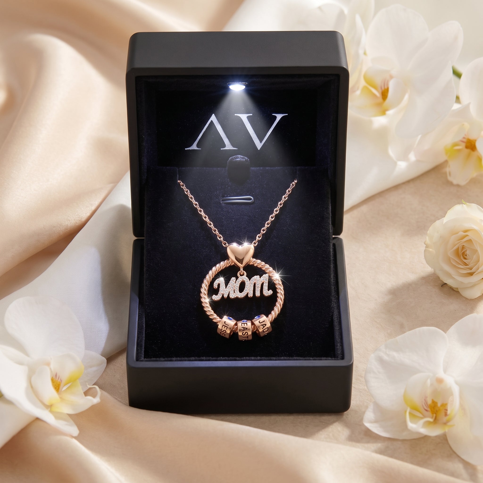 Rose gold Kalisene necklace displayed in a black LED-lit jewelry box surrounded by white flowers.