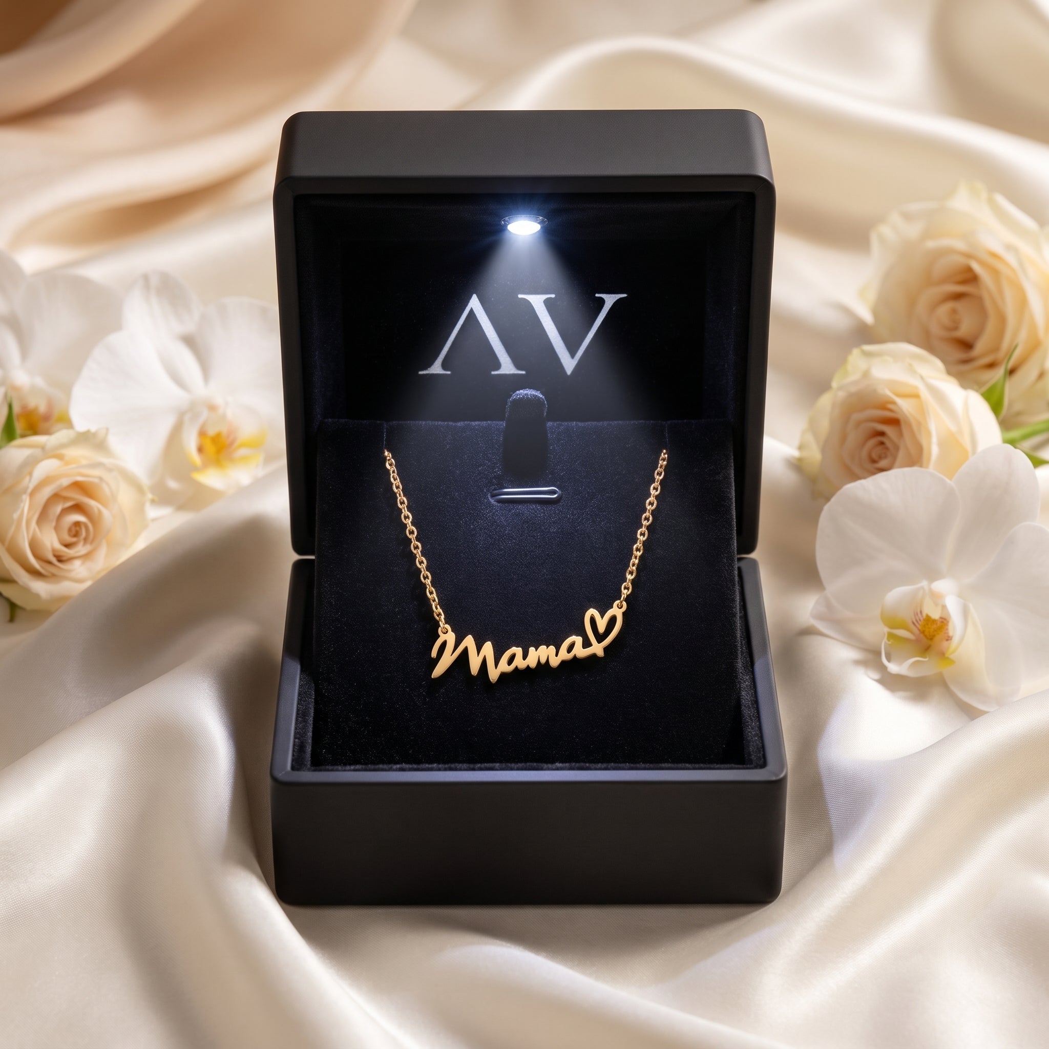 Gold Mama script necklace in a black LED-lit gift box with white roses and silk background.