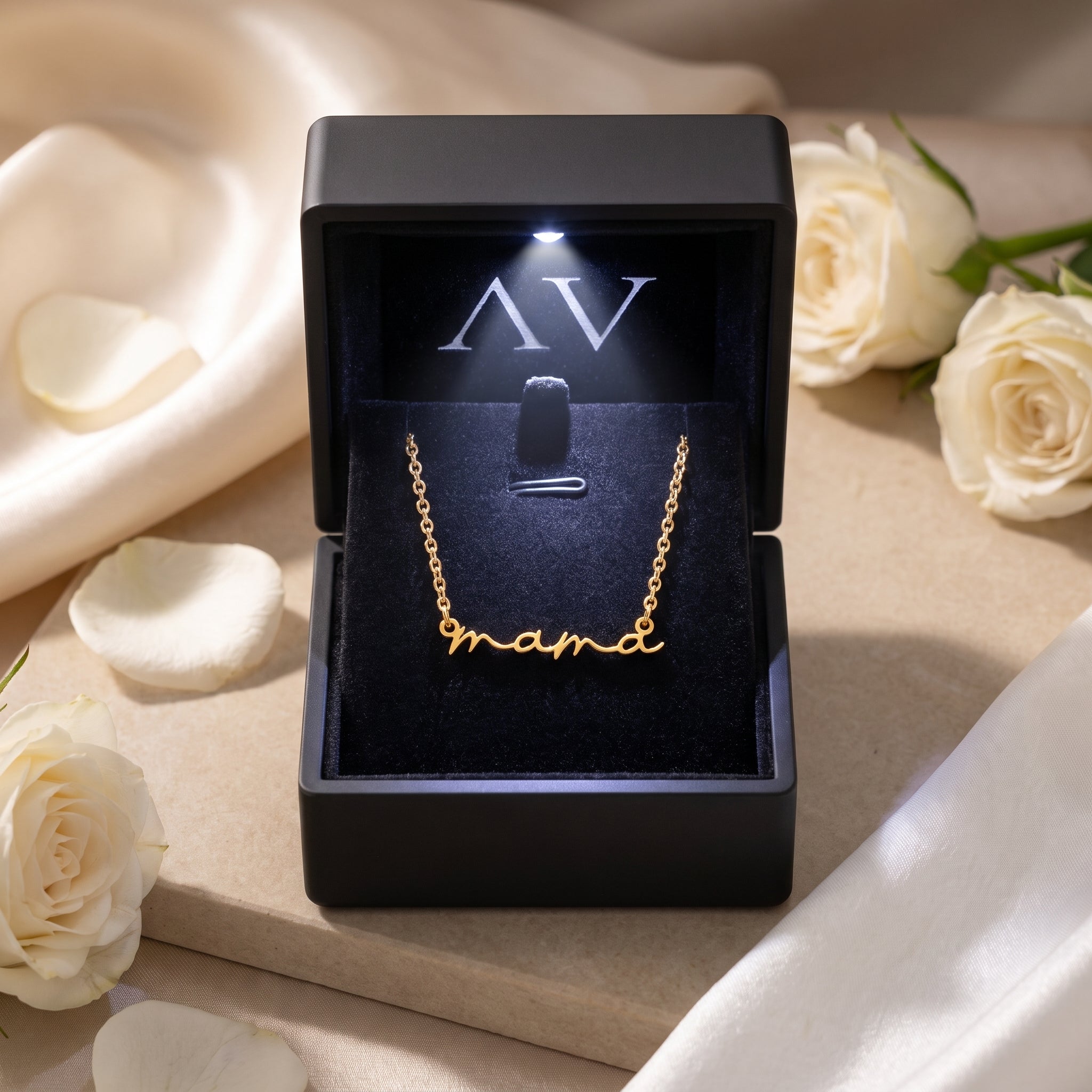 Gold mama script necklace inside an illuminated black gift box.