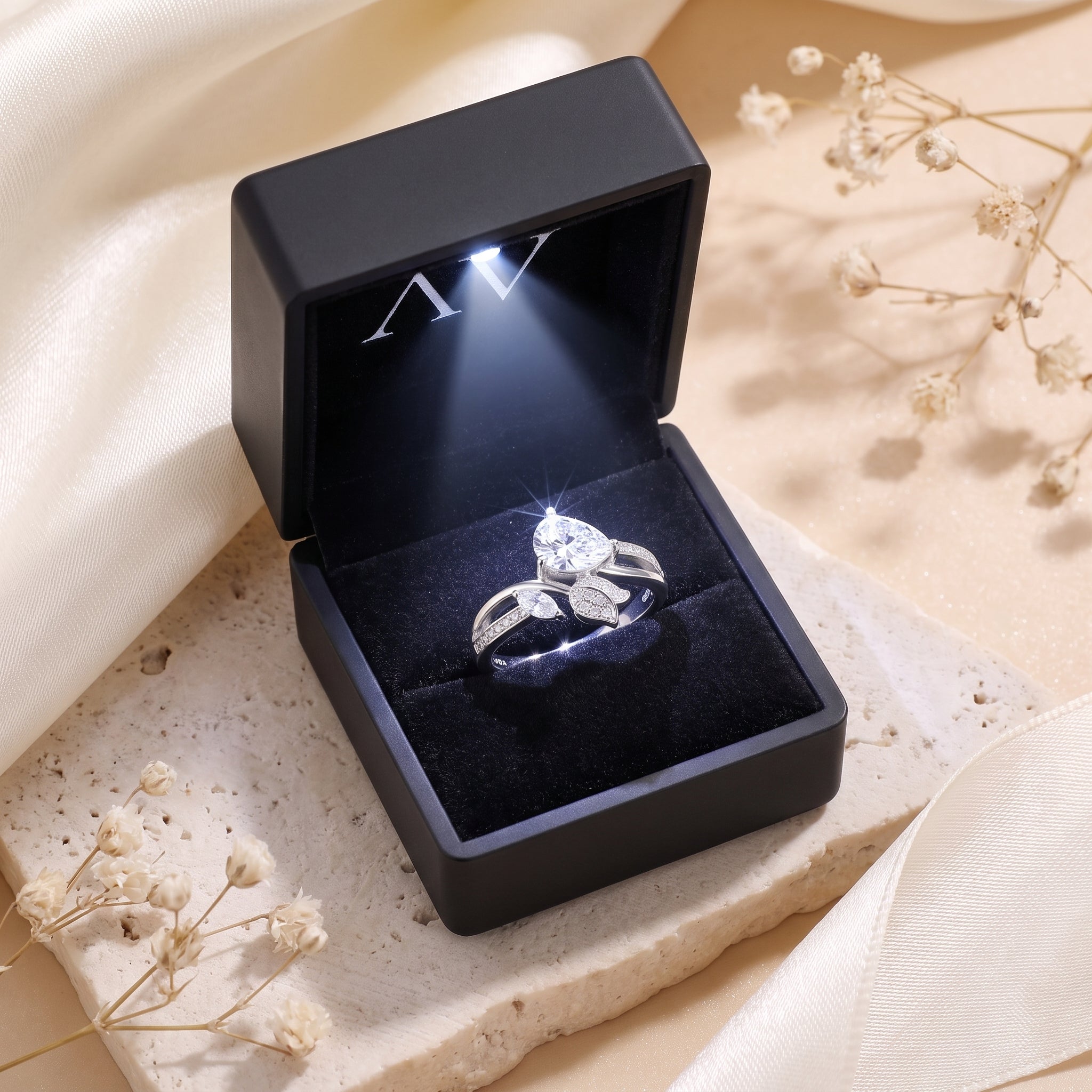 Silver pear-cut simulated diamond leaf ring inside a black LED-lit jewelry presentation box.
