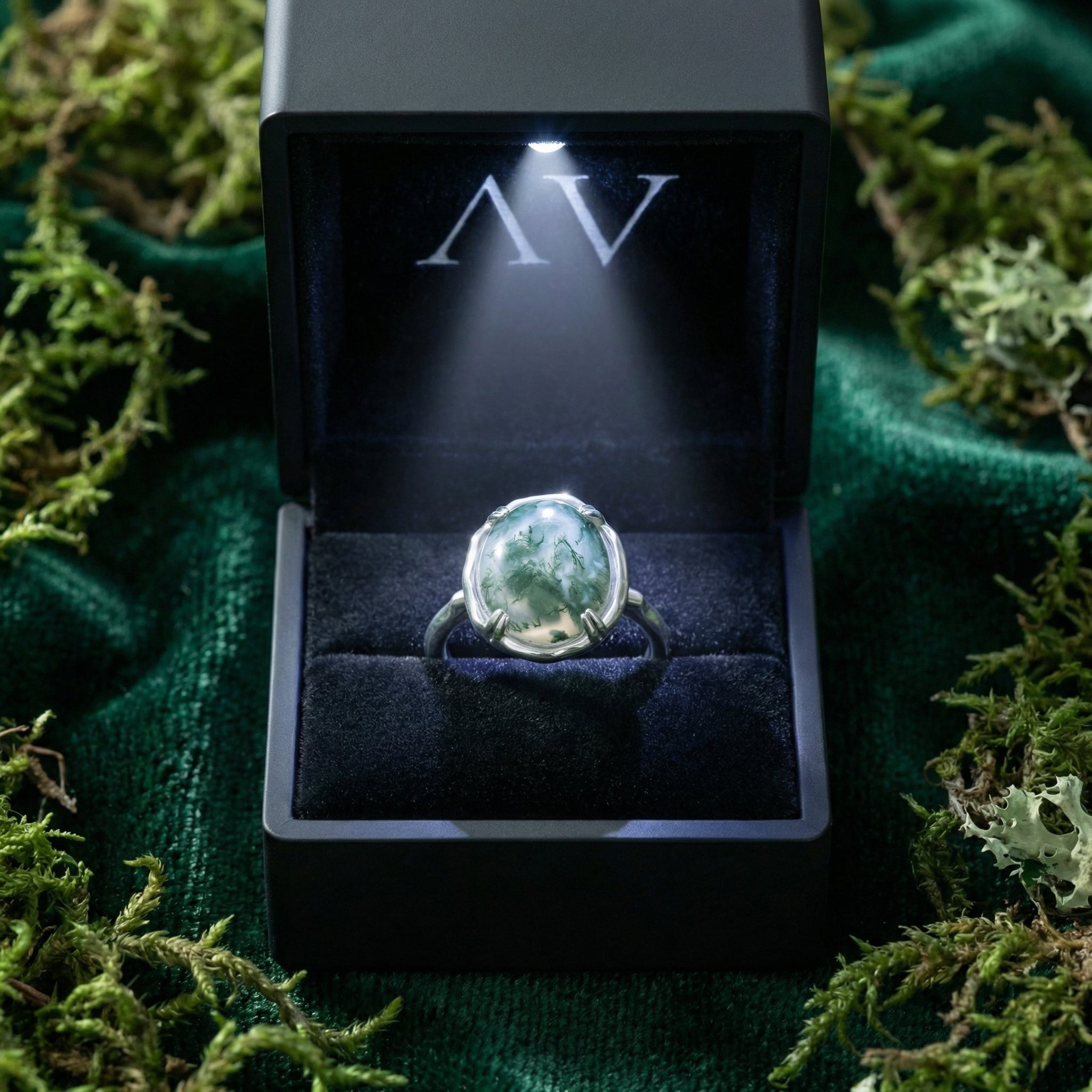 Natural moss agate sterling silver ring presented in a black illuminated gift box on a bed of green moss.