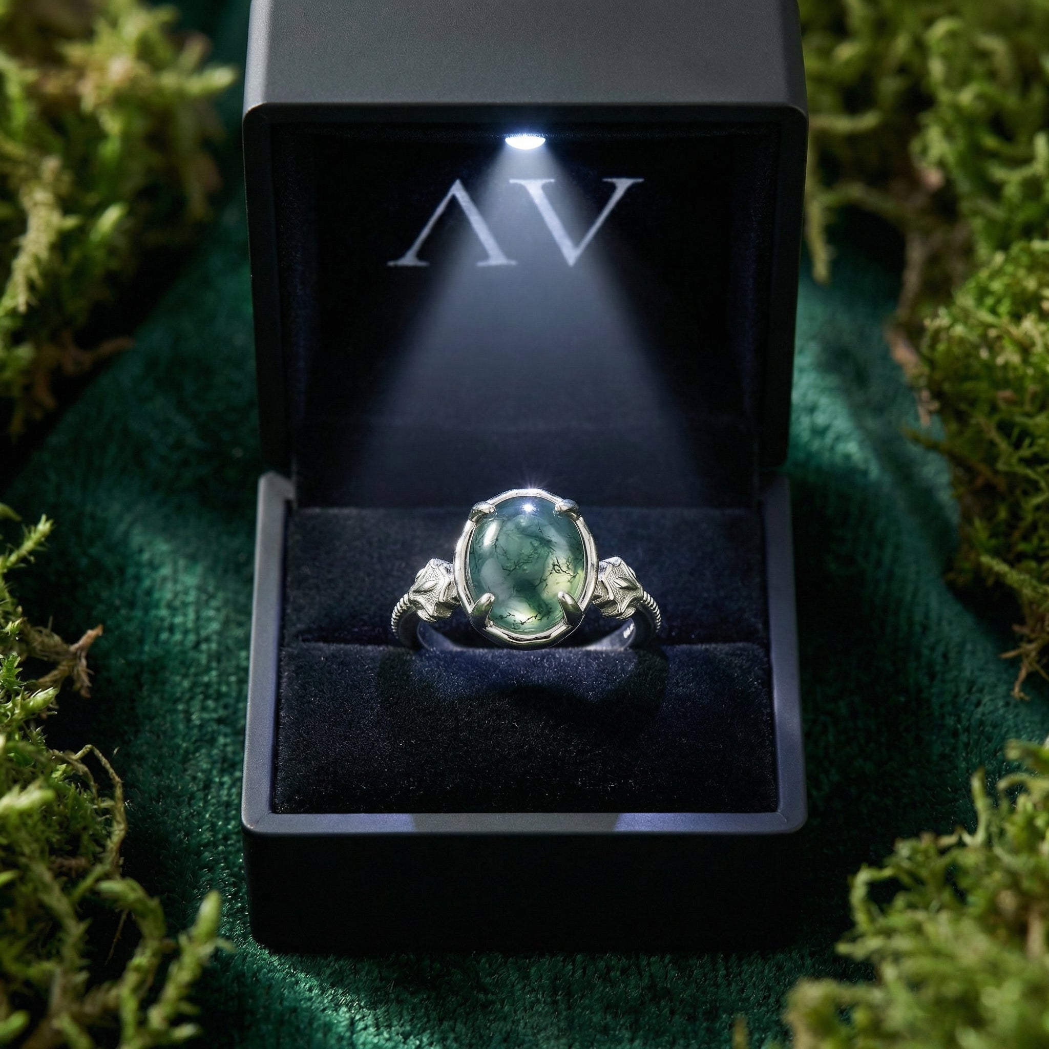 Oval natural moss agate ring in S925 sterling silver presented in a black lighted gift box on moss.
