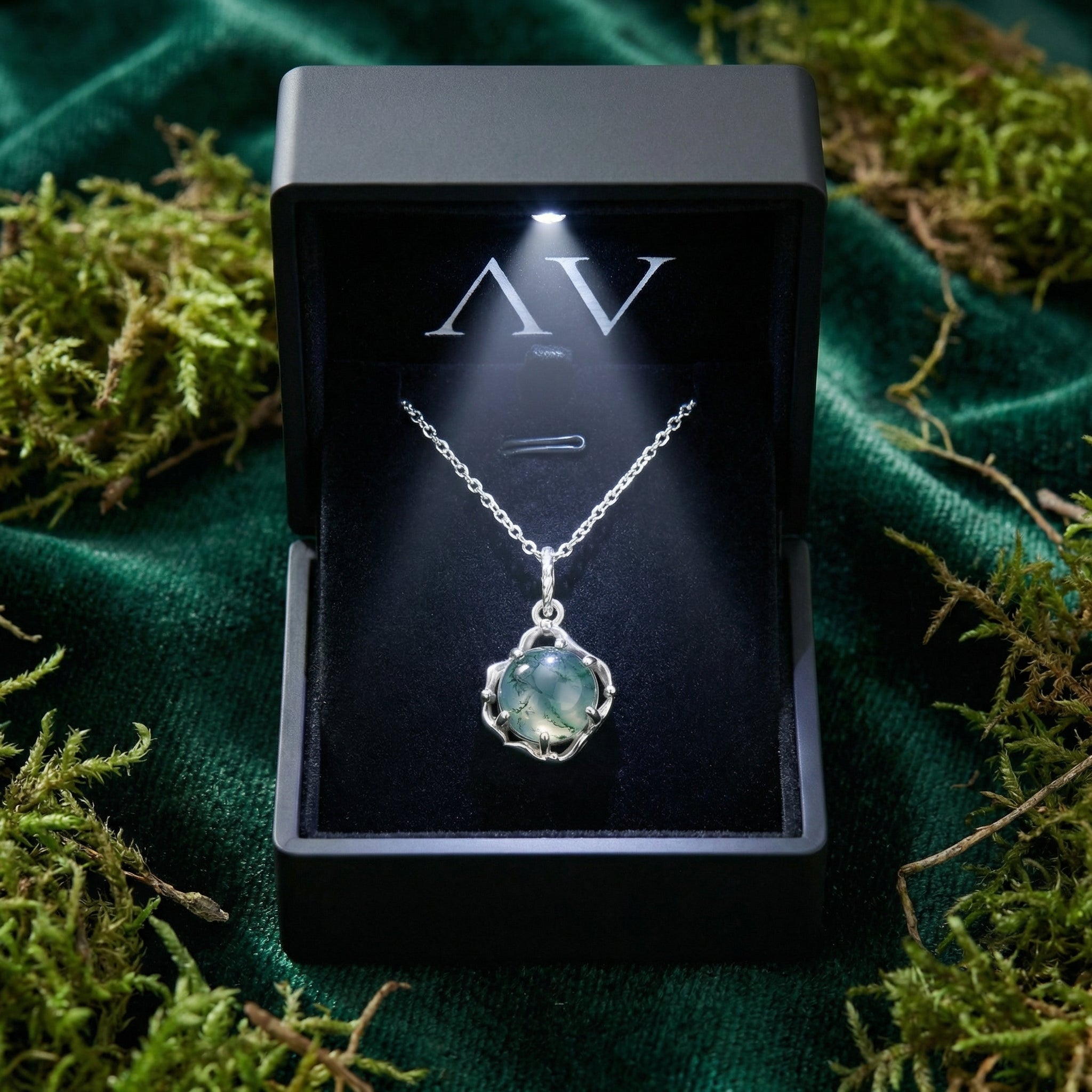 Sterling silver moss agate necklace presented in a lighted black gift box on a bed of green moss and velvet.