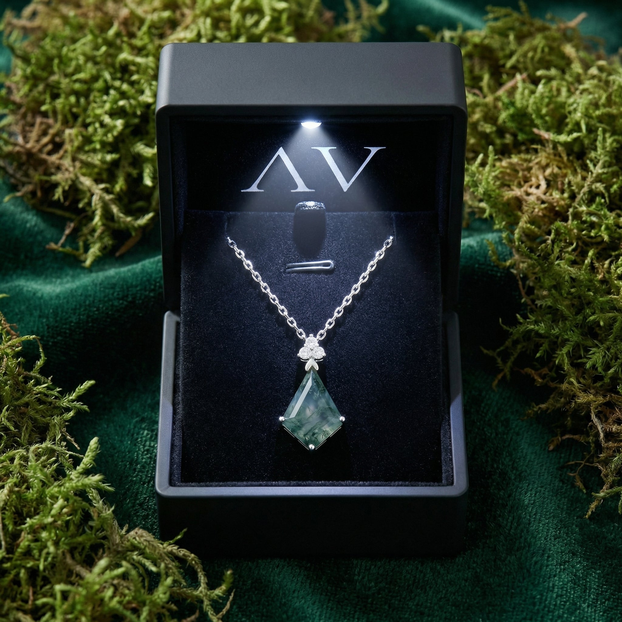 Sterling silver moss agate necklace presented in a black LED-lit gift box on a mossy background.